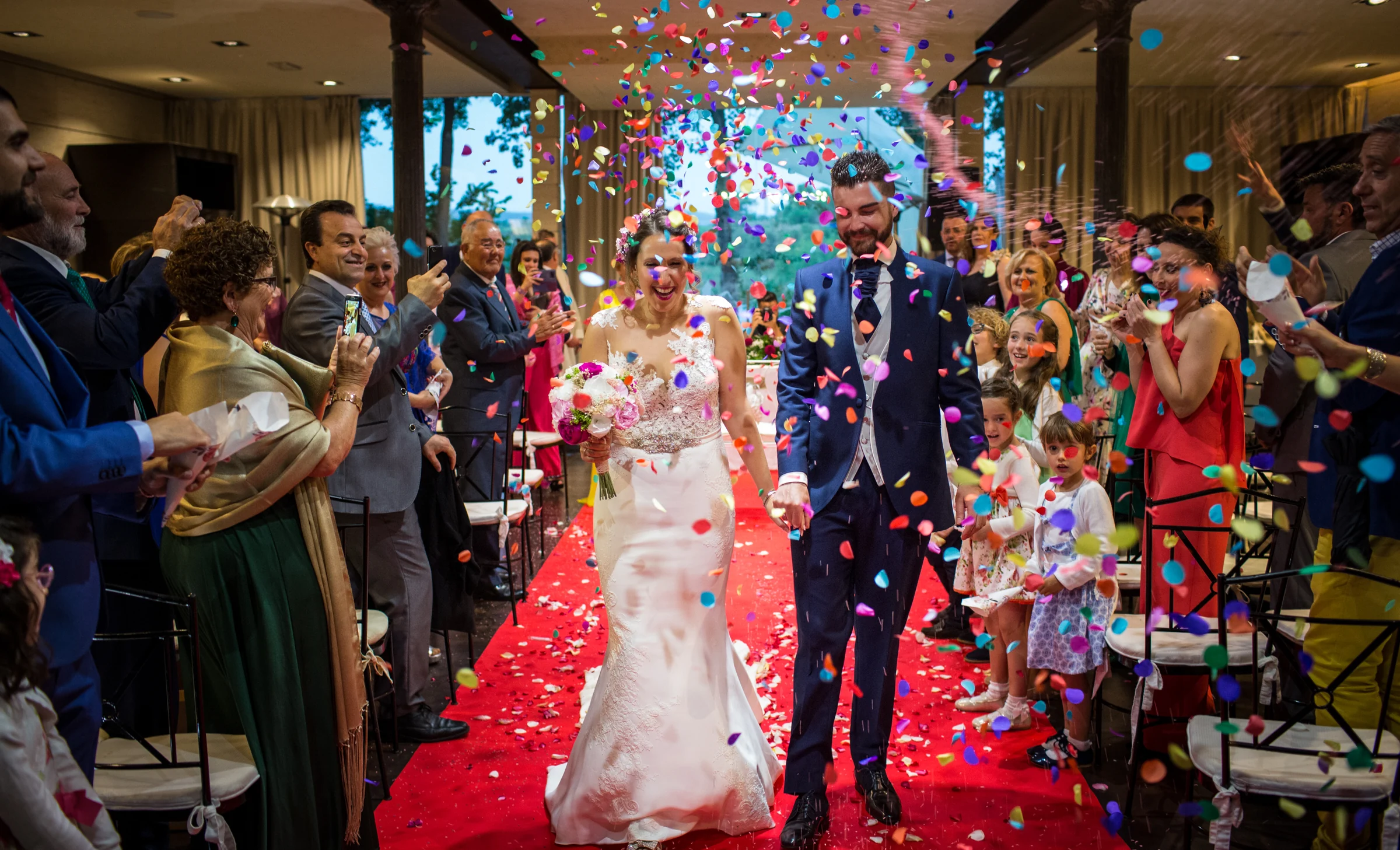 Salida de los novios entre confeti en el banquete en una boda en Complejo La Cigüeña