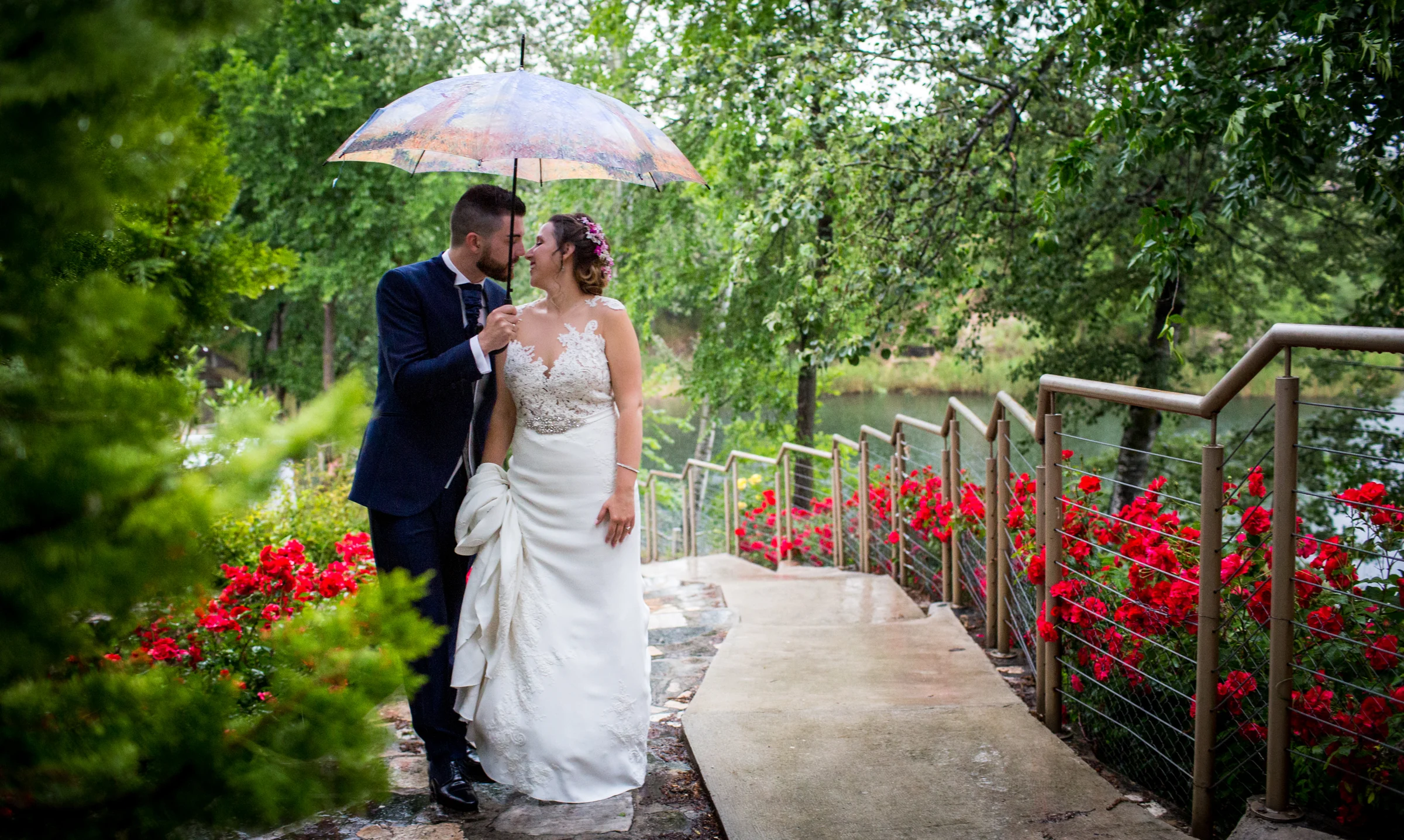 Novios bajo paraguas en un jardín en una boda en Complejo La Cigüeña