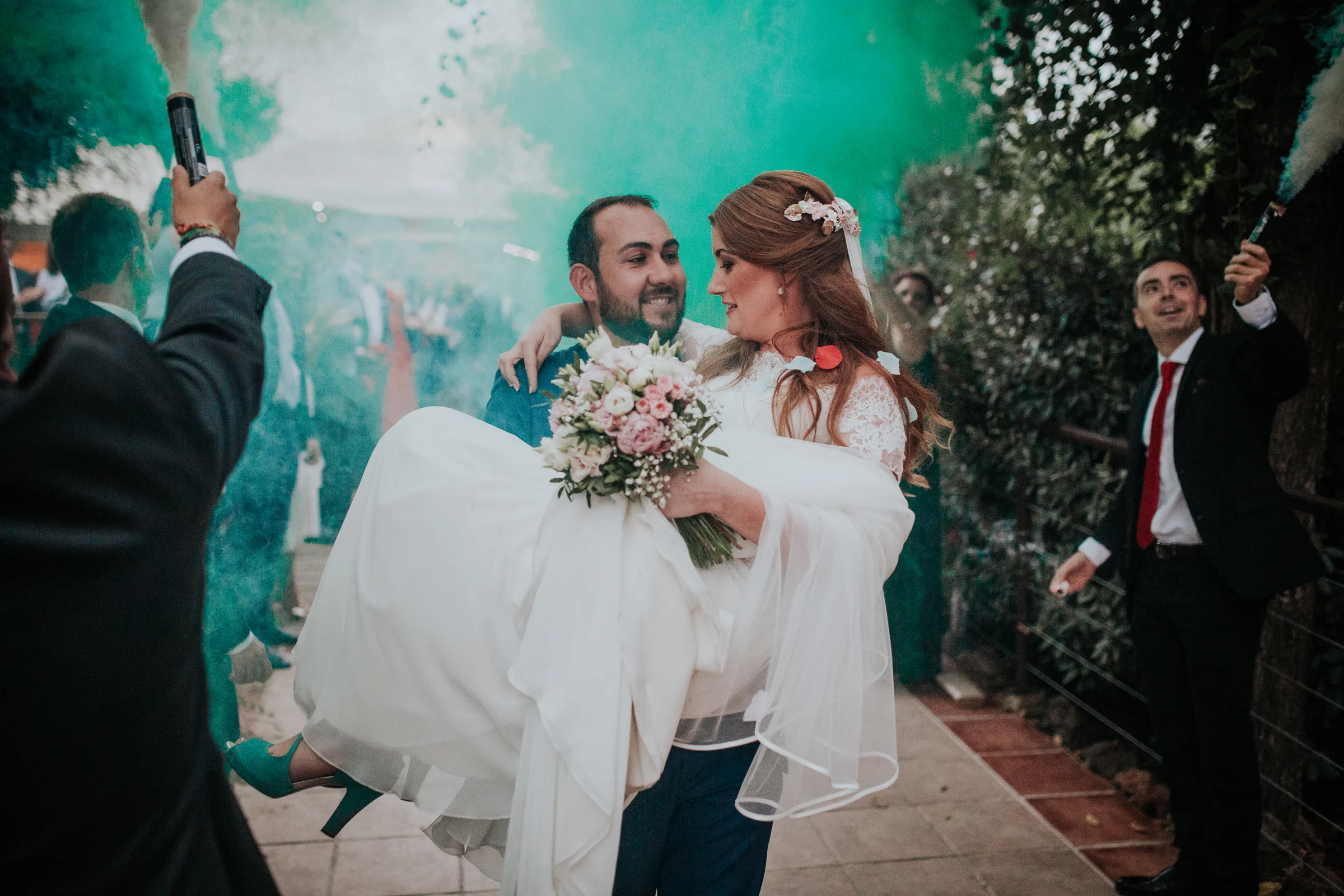 Novio llevando a la novia entre humo de colores en una boda en Complejo La Cigüeña