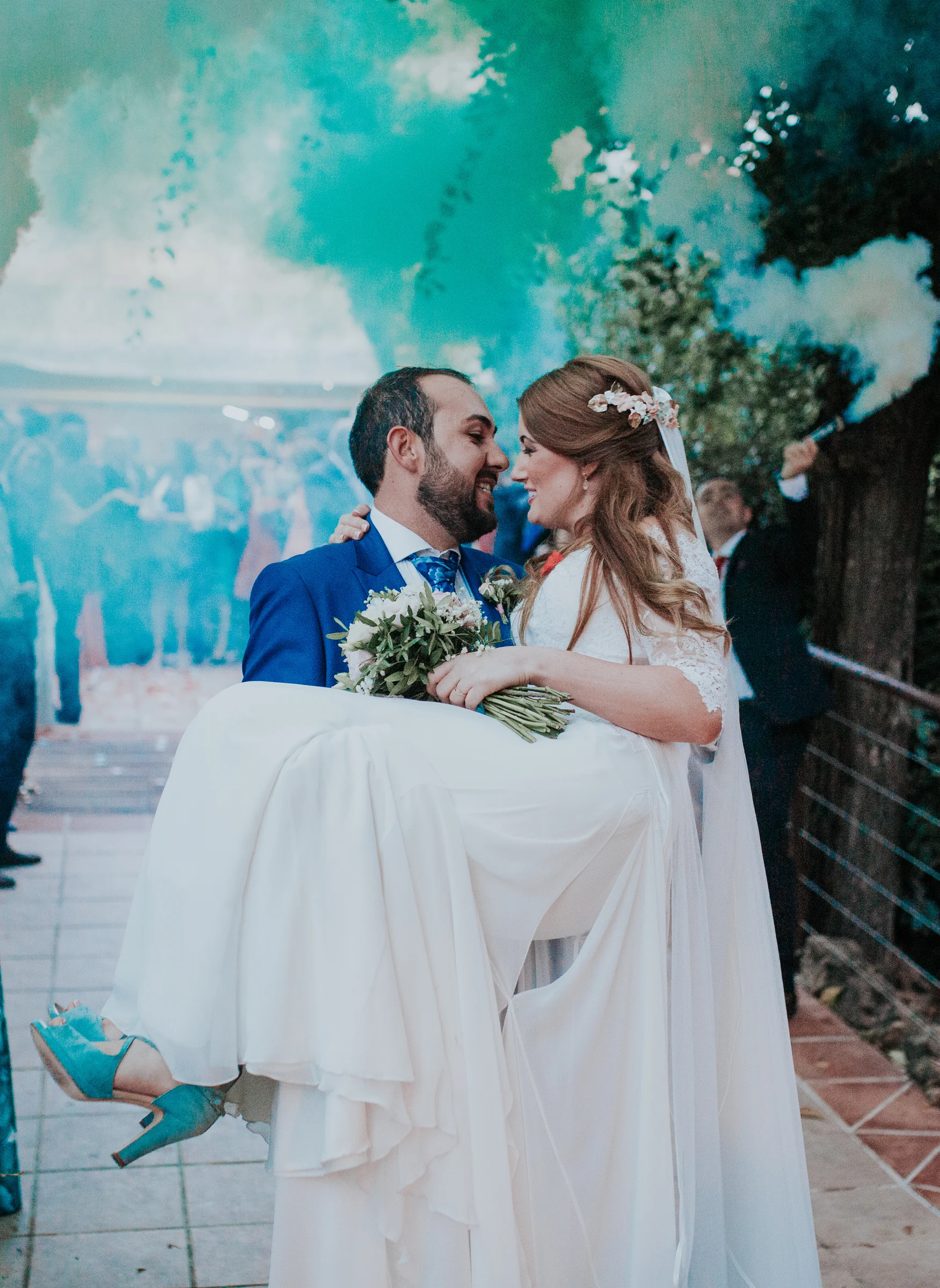 Novios abrazados entre humo de colores en una boda en Complejo La Cigüeña