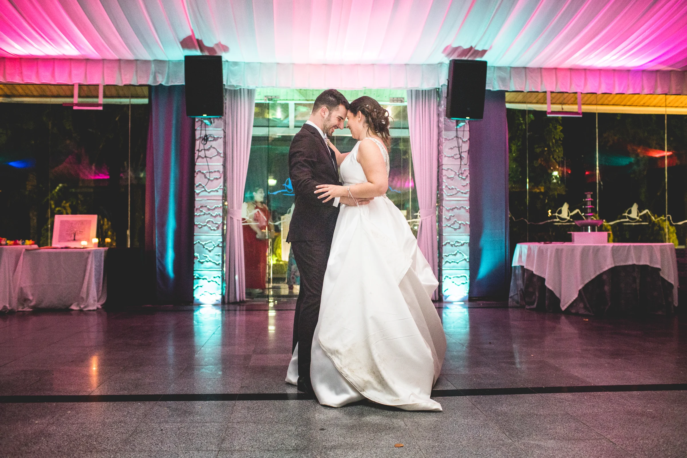 Novios bailando en el salón con iluminación de fiesta en una boda en Complejo La Cigüeña