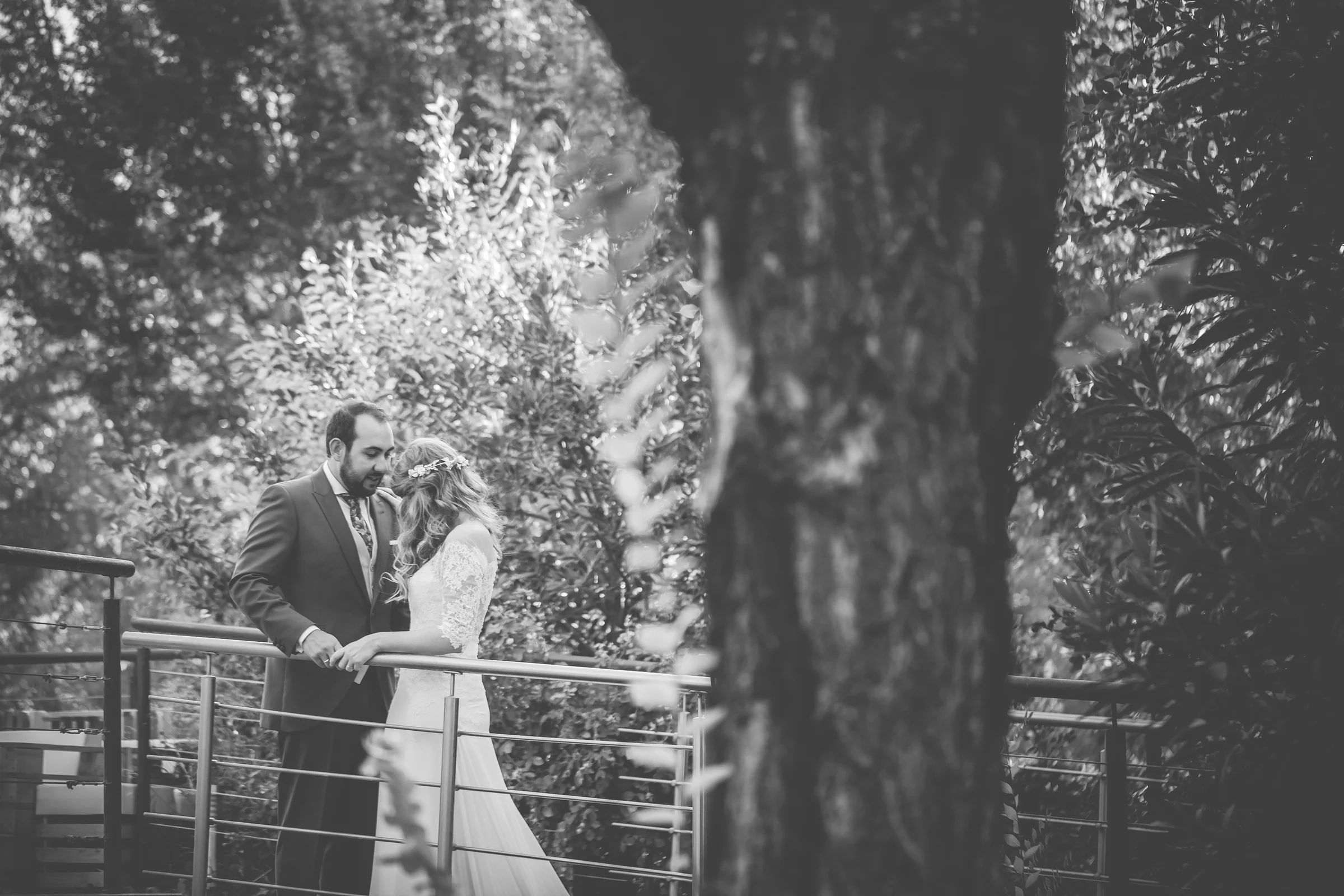 Novios apoyados en una barandilla en blanco y negro en una boda en Complejo La Cigüeña