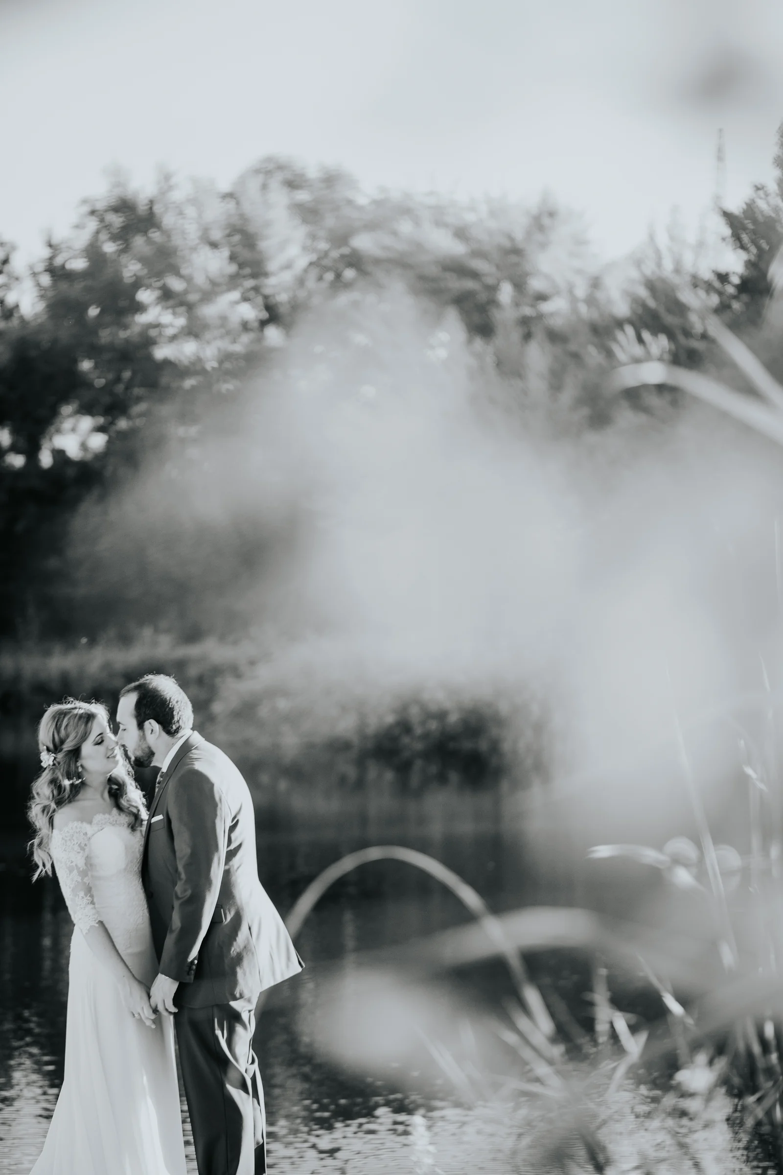 Novios retratados entre vegetación en blanco y negro en una boda en Complejo La Cigüeña