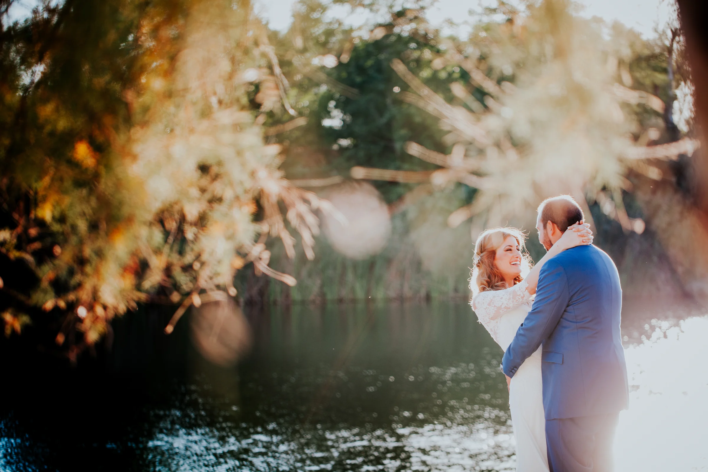 Novios junto al lago con luz de atardecer en una boda en Complejo La Cigüeña