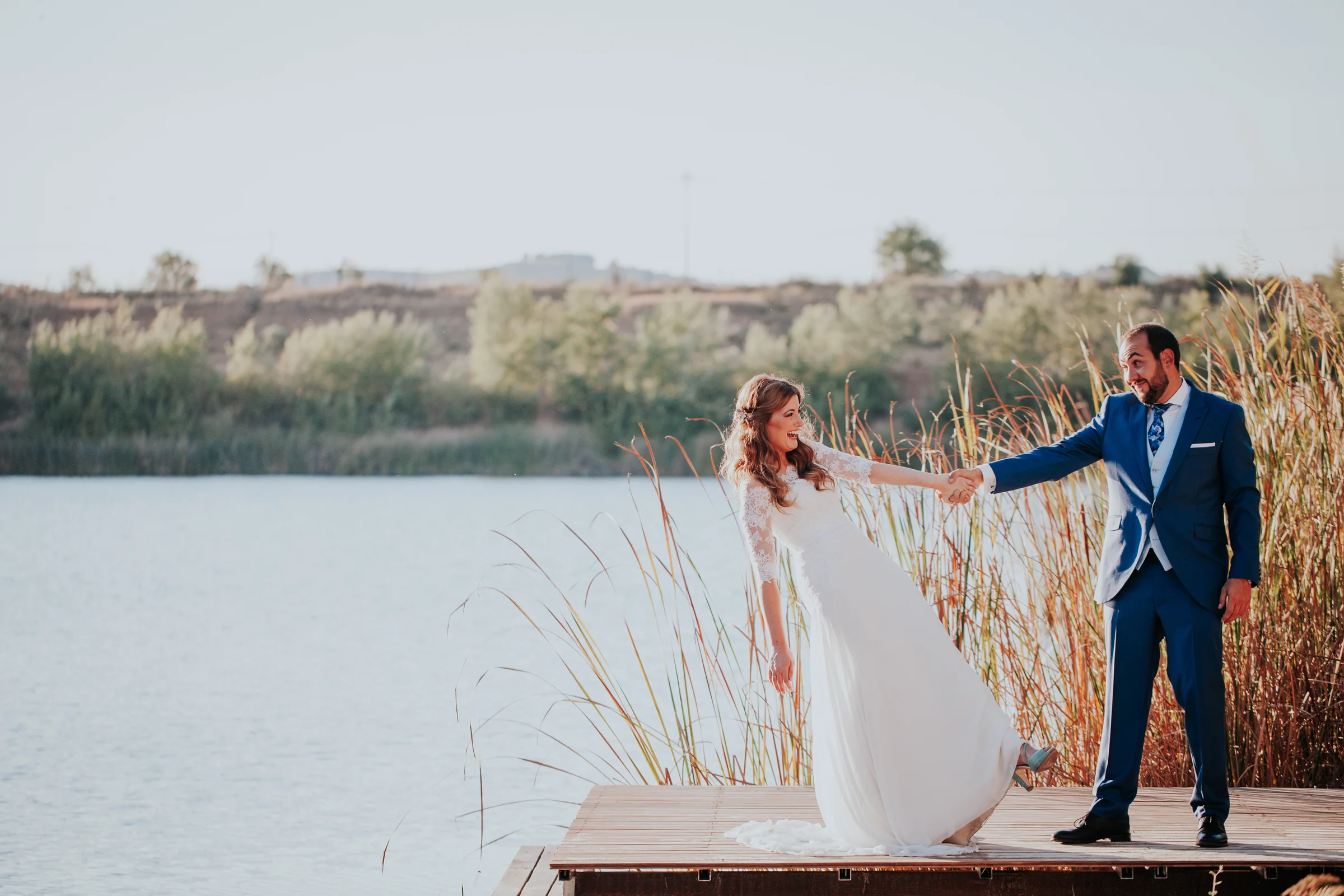 Novios frente al lago con paisaje abierto en una boda en Complejo La Cigüeña
