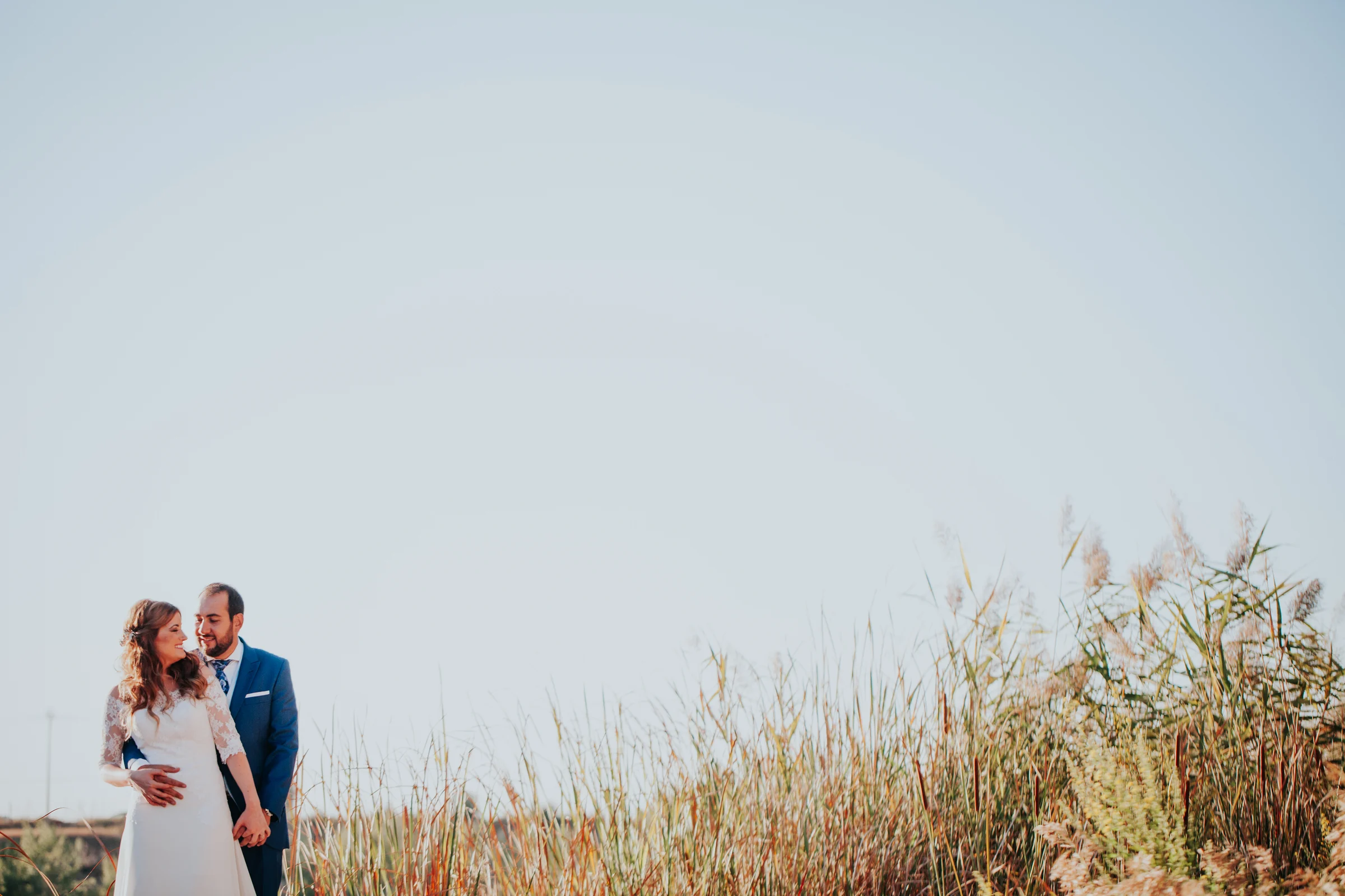 Novios en un paisaje abierto junto al lago en una boda en Complejo La Cigüeña