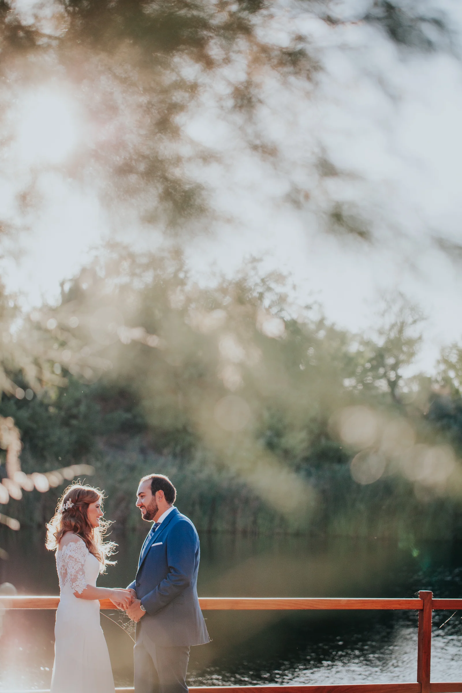 Novios junto al lago en encuadre vertical en una boda en Complejo La Cigüeña