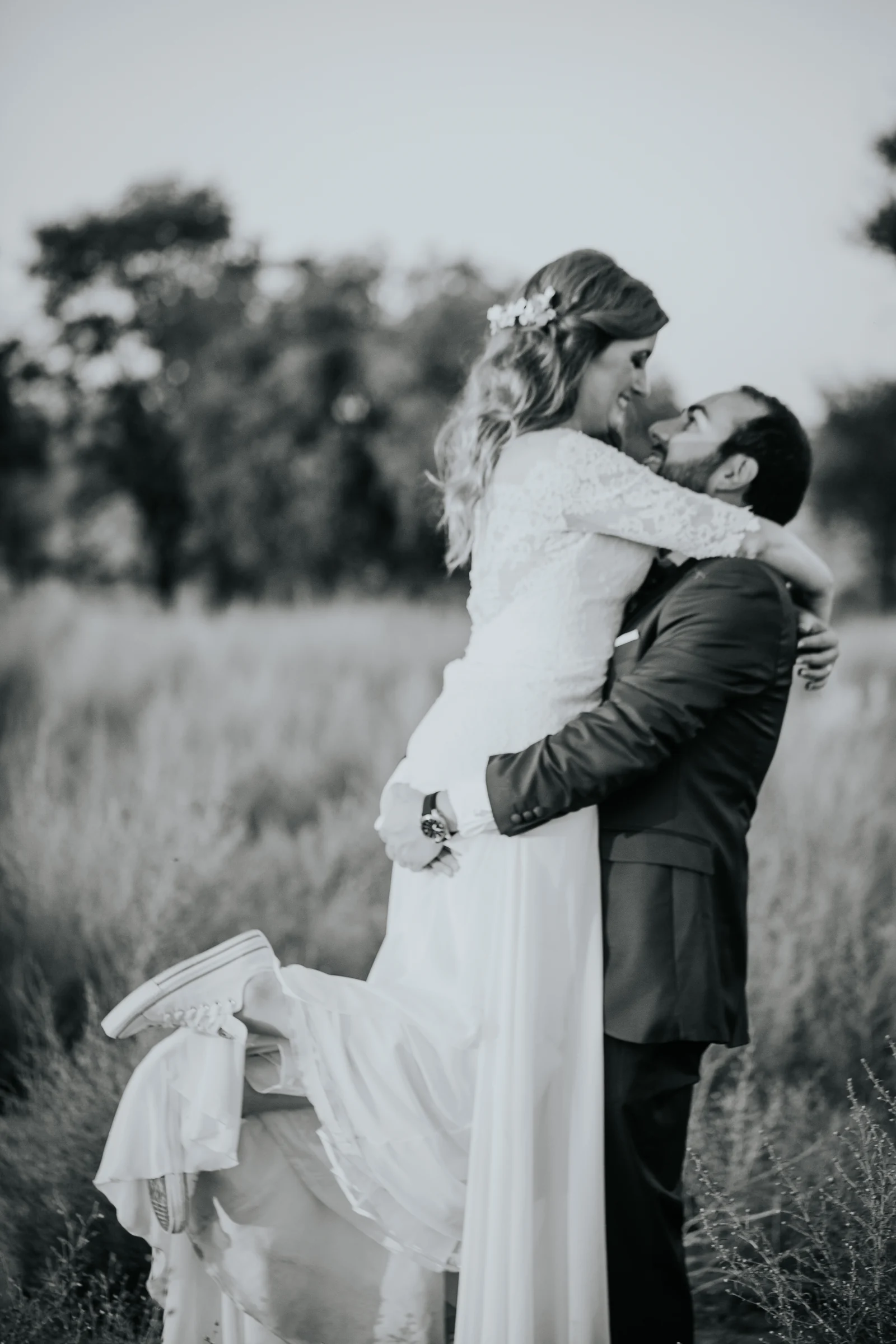 Novios abrazándose en un prado en blanco y negro en una boda en Complejo La Cigüeña