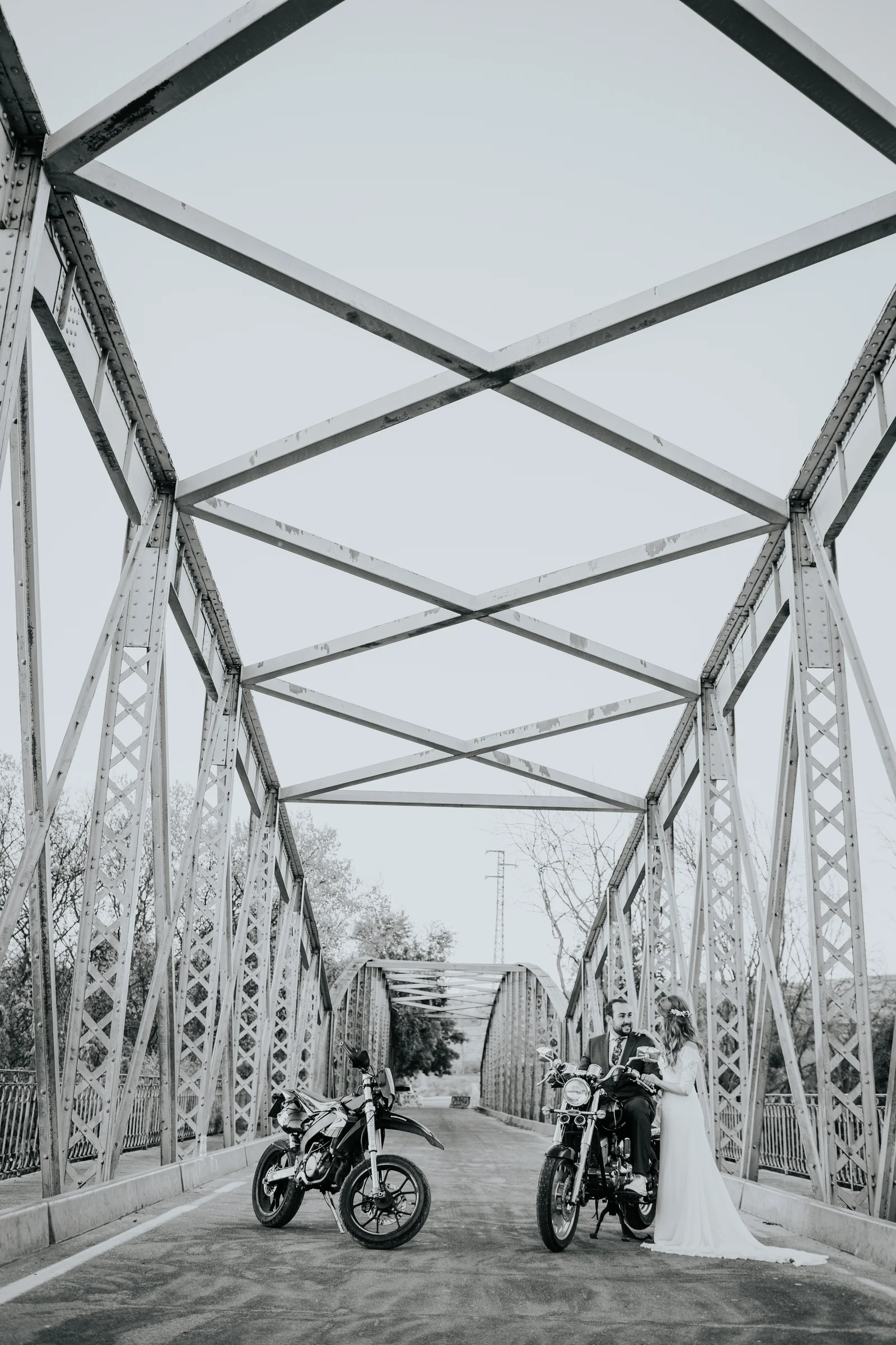 Motocicleta en un puente metálico con los novios al fondo en una boda en Complejo La Cigüeña