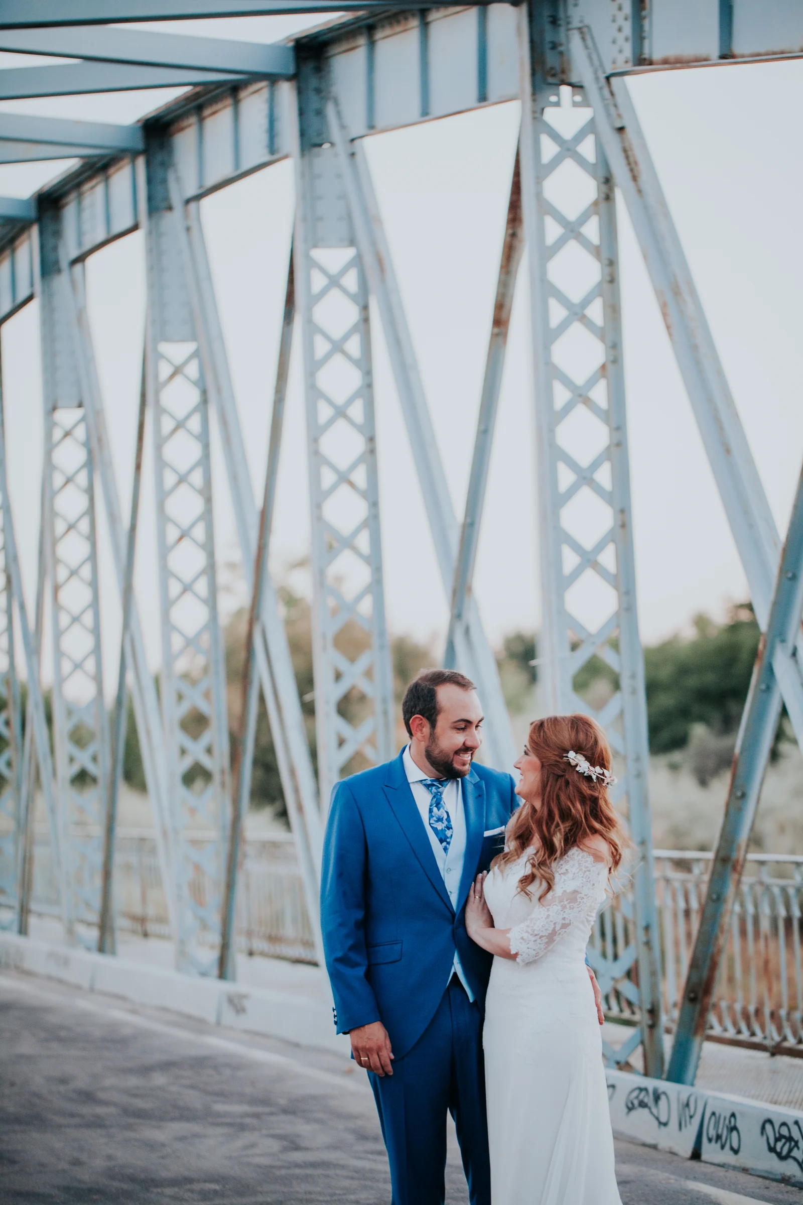 Novios en un puente metálico en encuadre vertical en una boda en Complejo La Cigüeña
