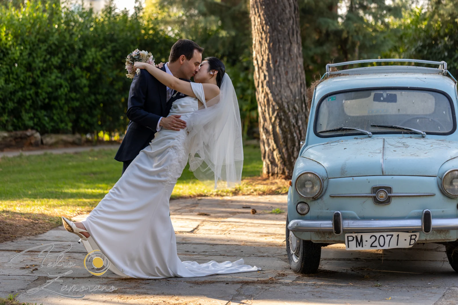 Beso de los novios junto a coche clasico durante una boda en Mirador de Cuatro Vientos.