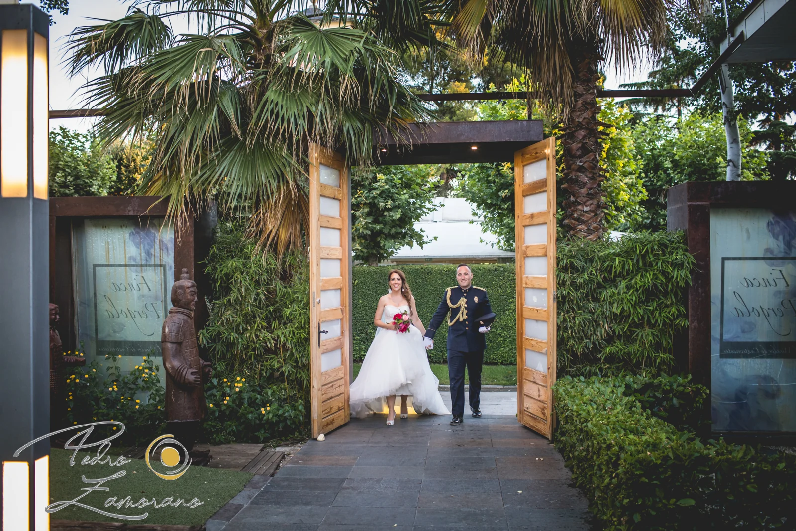 Novios entrando por puerta de jardin durante una boda en Mirador de Cuatro Vientos.
