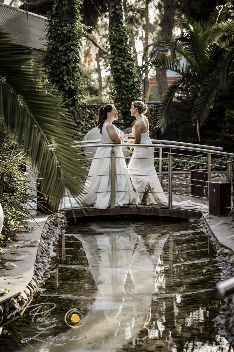 Dos novias sobre puente con reflejo durante una boda en Mirador de Cuatro Vientos.