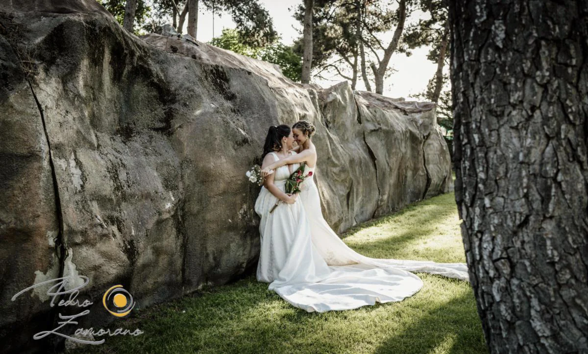 Dos novias abrazadas junto a roca durante una boda en Mirador de Cuatro Vientos.
