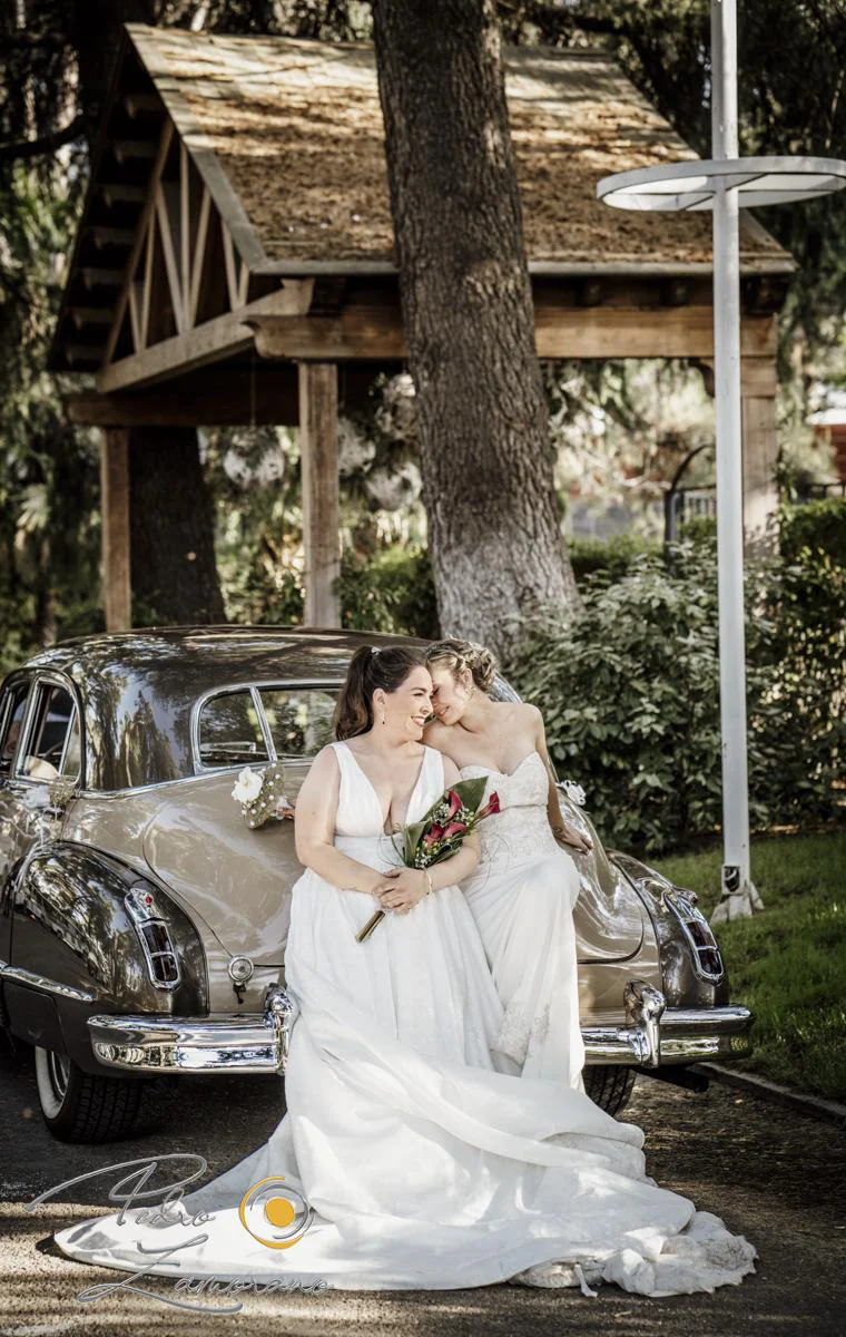Dos novias junto a coche clasico durante una boda en Mirador de Cuatro Vientos.