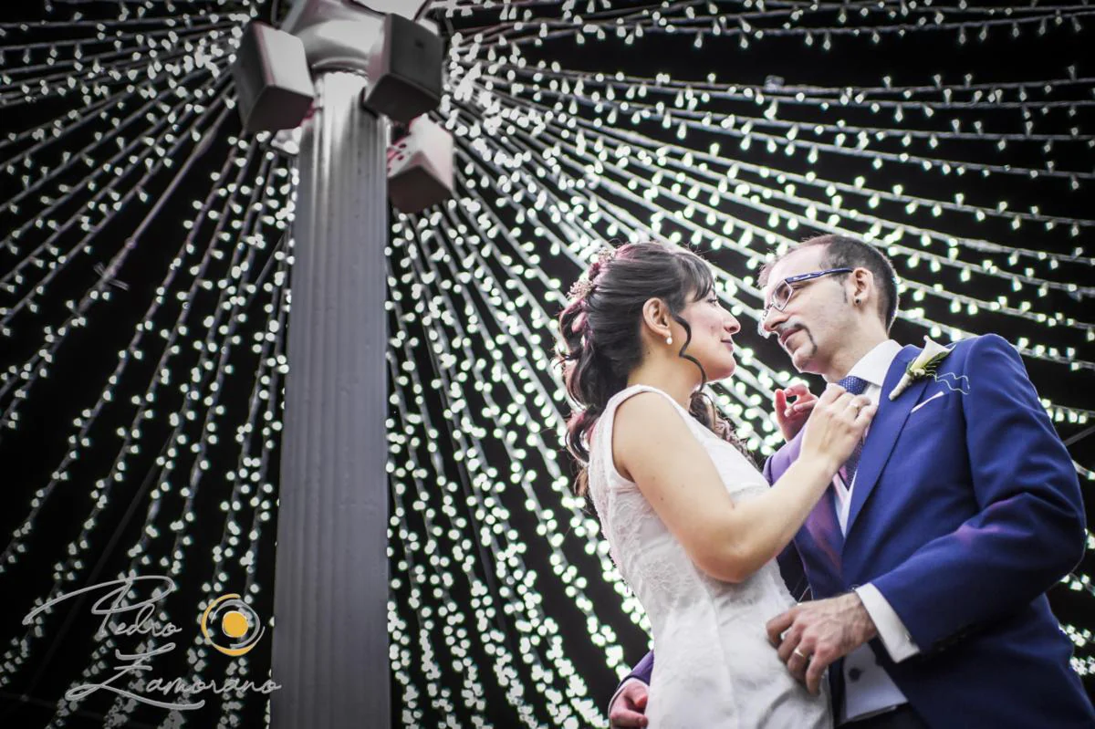 Novios bajo guirnaldas luminosas durante una boda en Mirador de Cuatro Vientos.