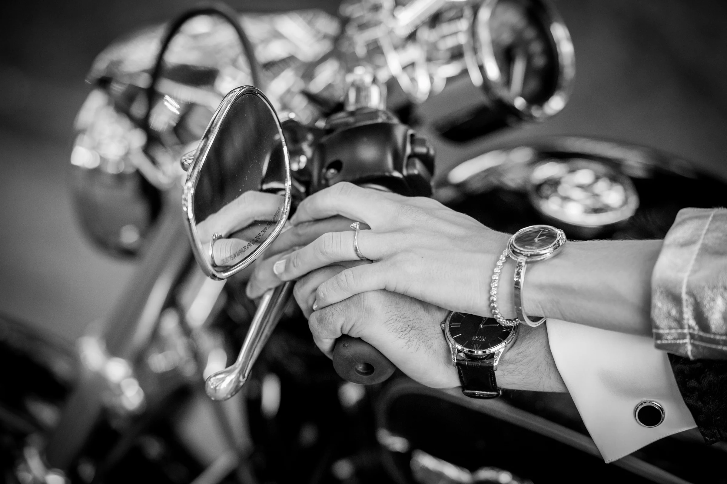 Manos de los novios sobre motocicleta en blanco y negro durante una boda en Mirador de Cuatro Vientos.