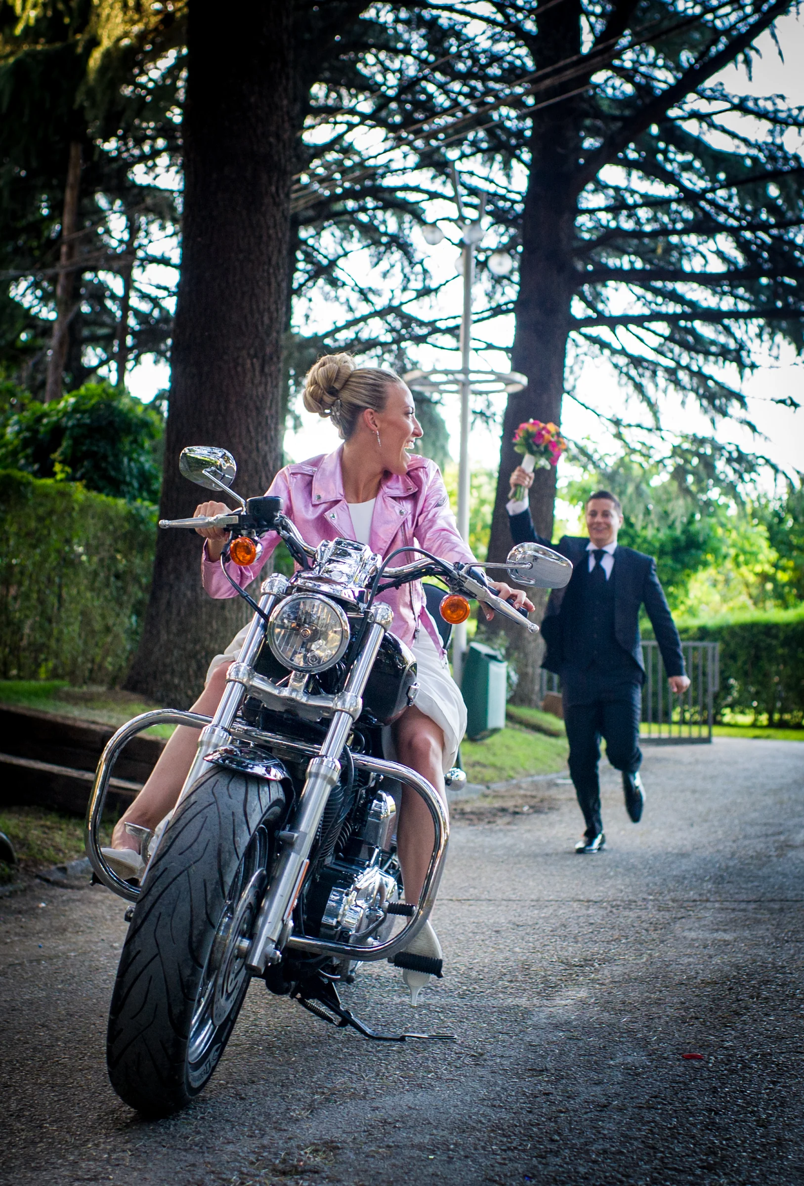 Novia sobre motocicleta y novio corriendo durante una boda en Mirador de Cuatro Vientos.