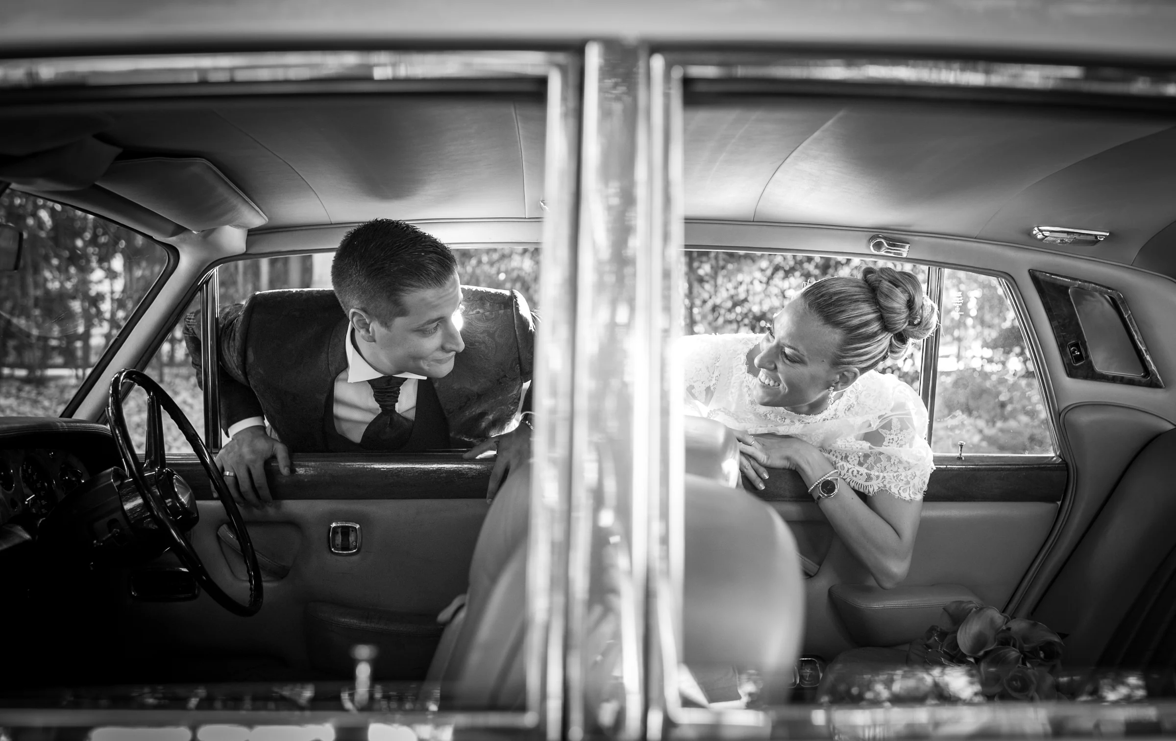 Novios asomados por ventanillas en blanco y negro durante una boda en Mirador de Cuatro Vientos.