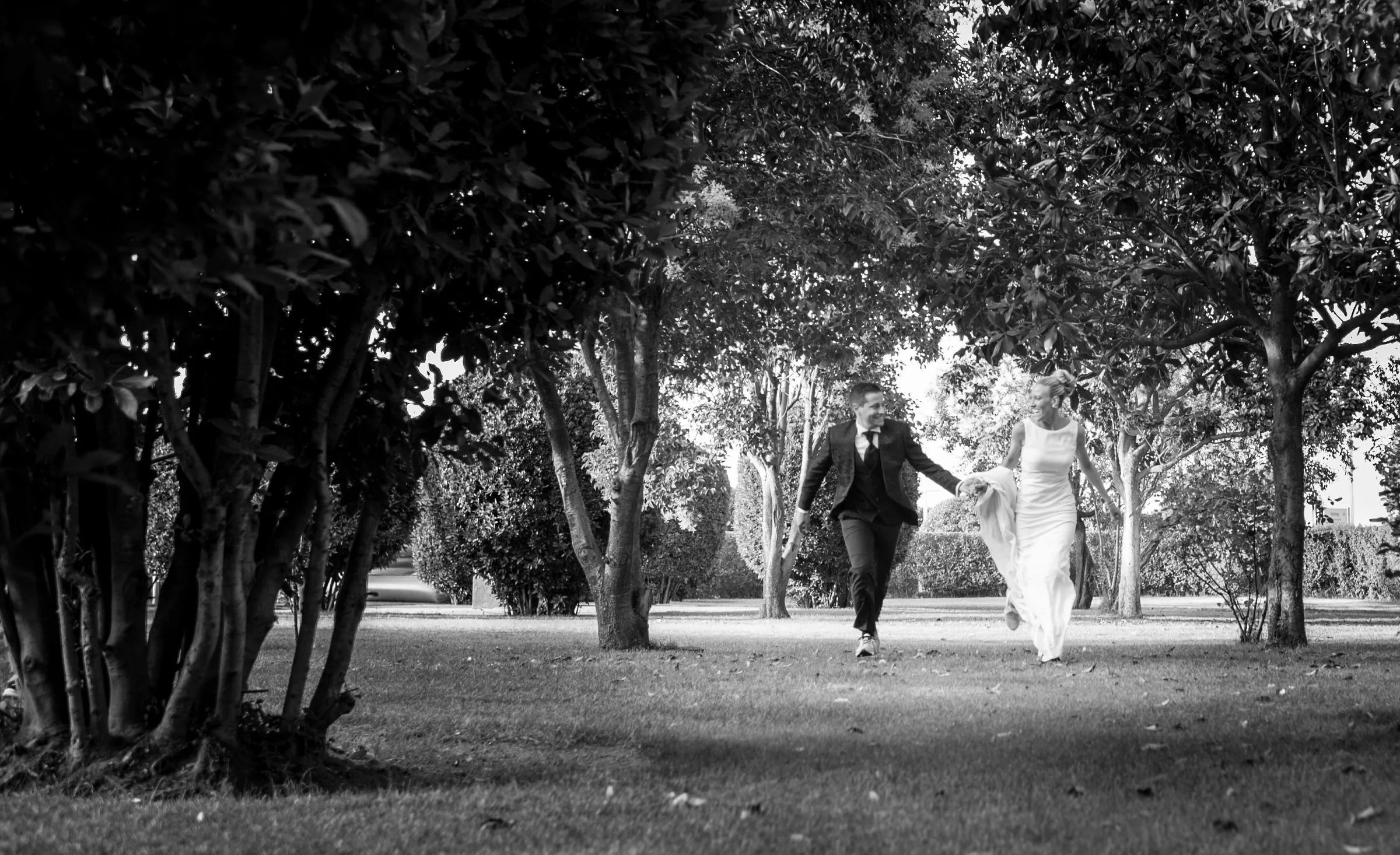 Novios corriendo por los jardines en blanco y negro durante una boda en Mirador de Cuatro Vientos.