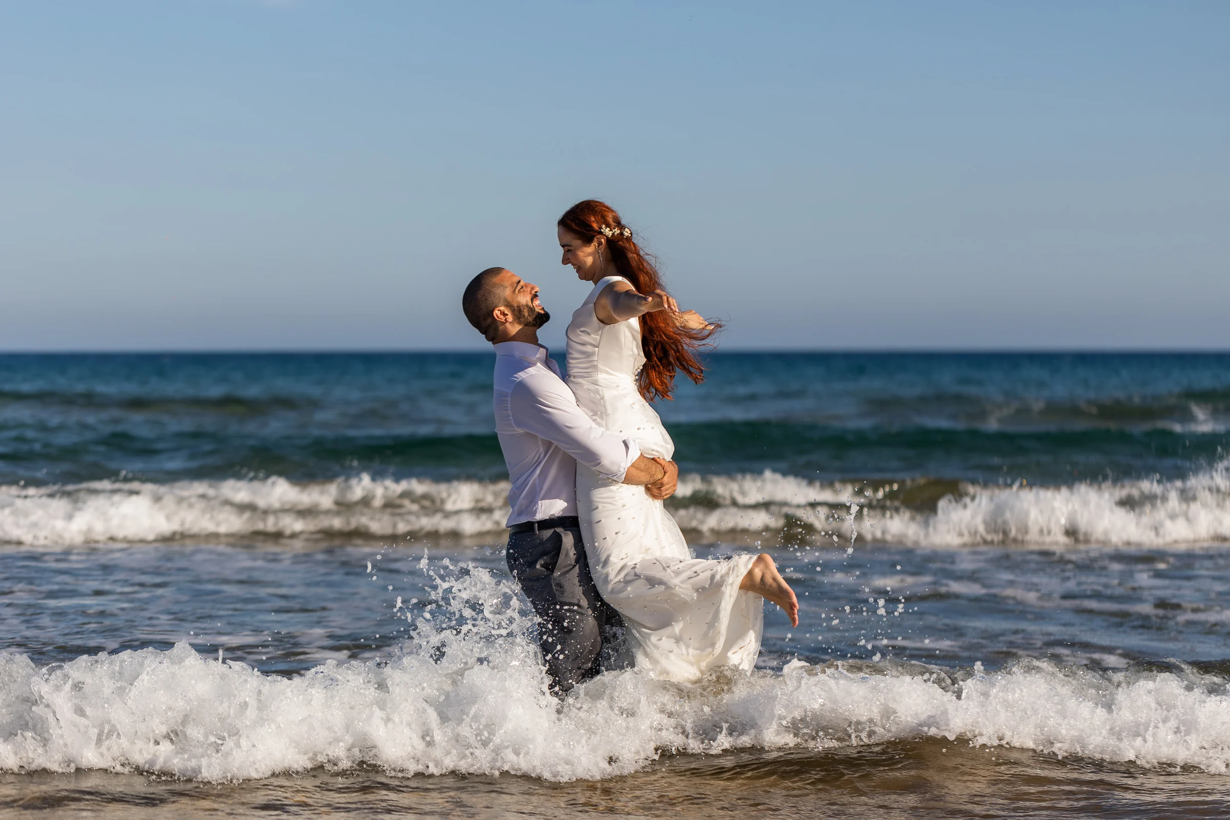 Fran levanta a Noemí dentro del mar mientras las olas rodean a la pareja en Cartagena.