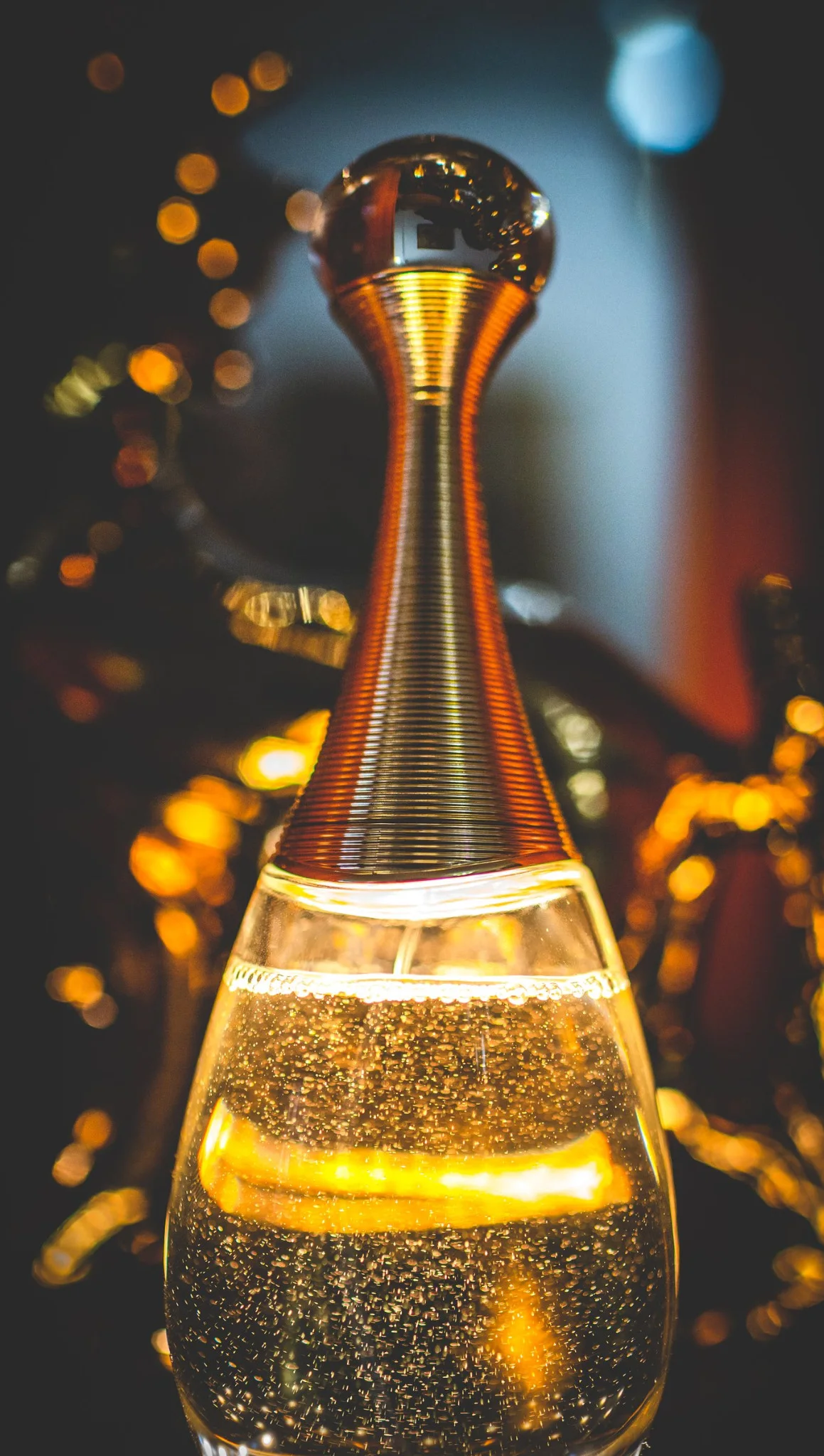 Frasco de perfume de la novia con luces desenfocadas en una boda en Peñarrubia de Araceli, fotografía de Pedro Zamorano.