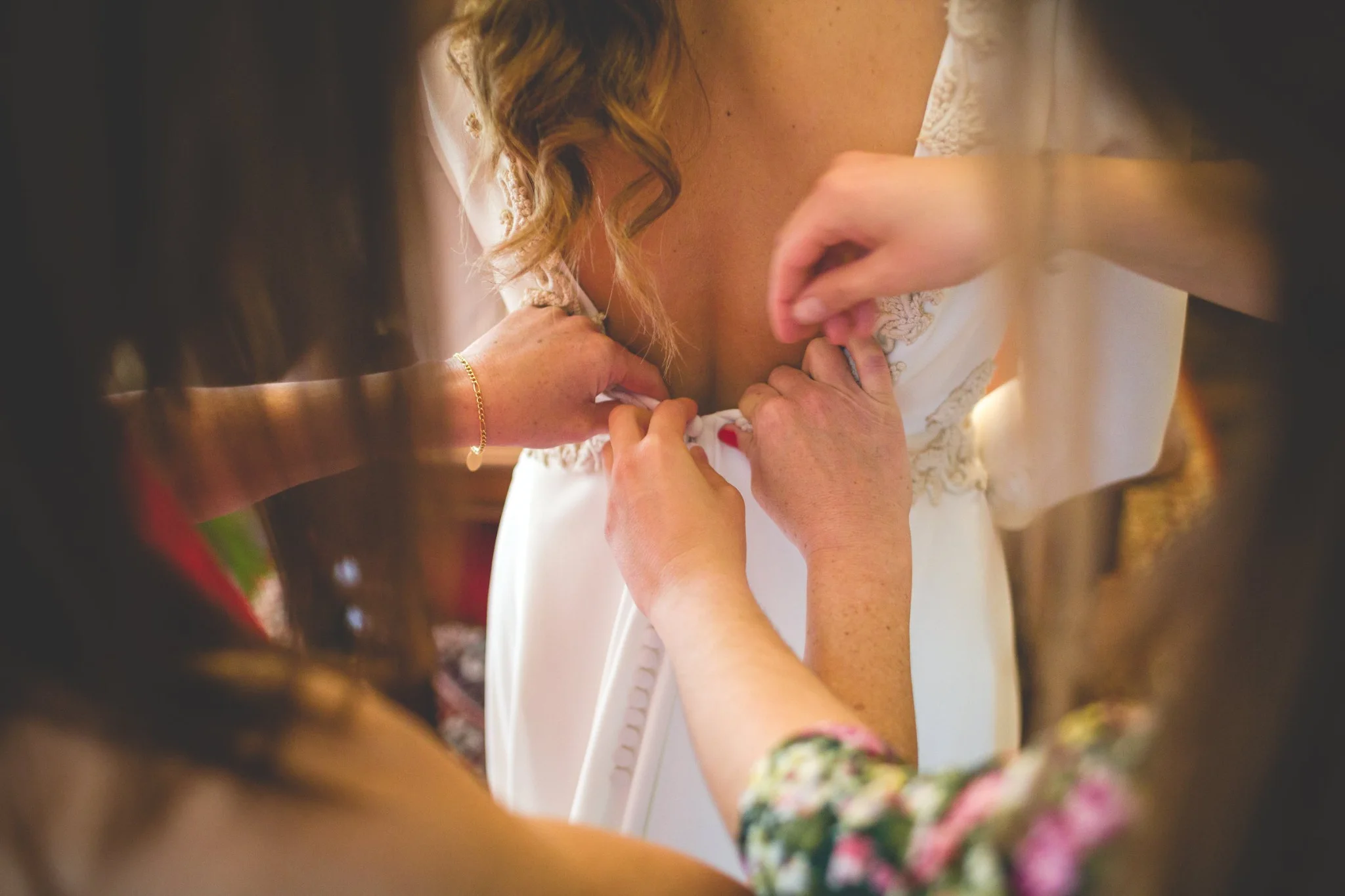 Detalle de manos abrochando el vestido de novia en una boda en Peñarrubia de Araceli, fotografía de Pedro Zamorano.