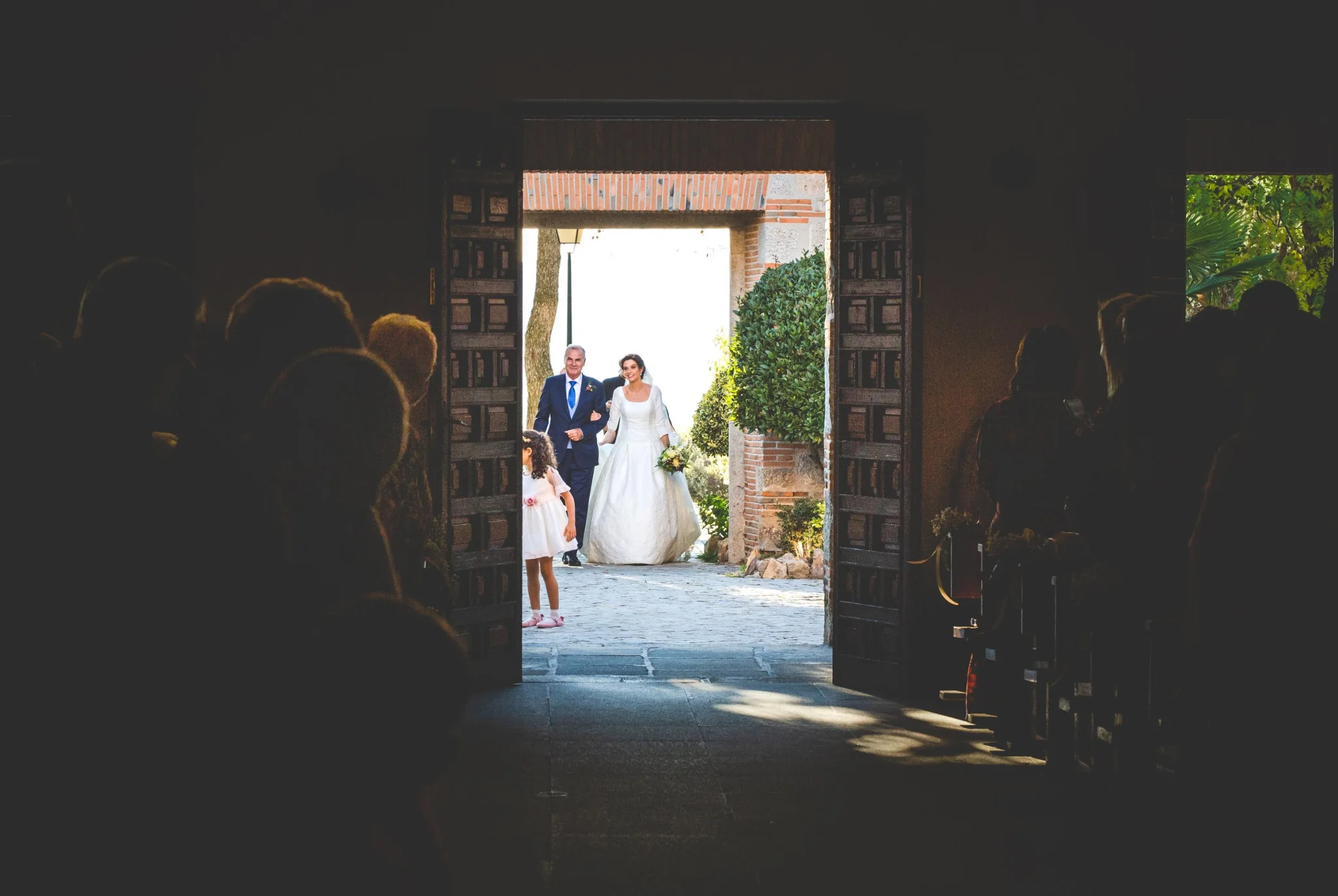 Entrada de la novia a la iglesia vista desde el interior en una boda en Peñarrubia de Araceli, fotografía de Pedro Zamorano.