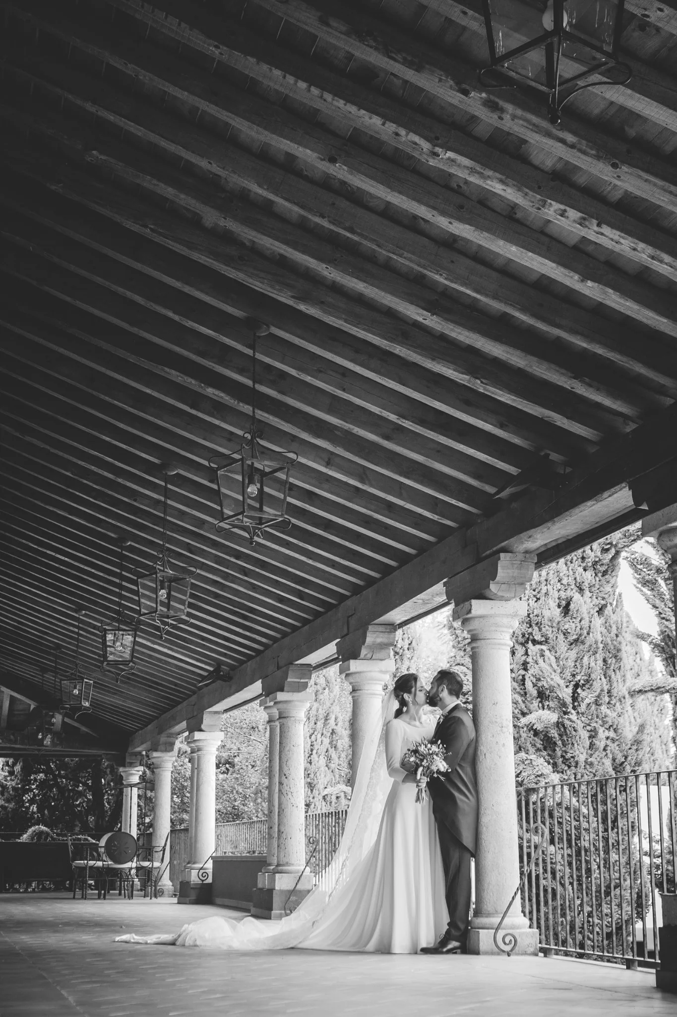 Retrato vertical en blanco y negro de los novios bajo el porche en una boda en Peñarrubia de Araceli, fotografía de Pedro Zamorano.