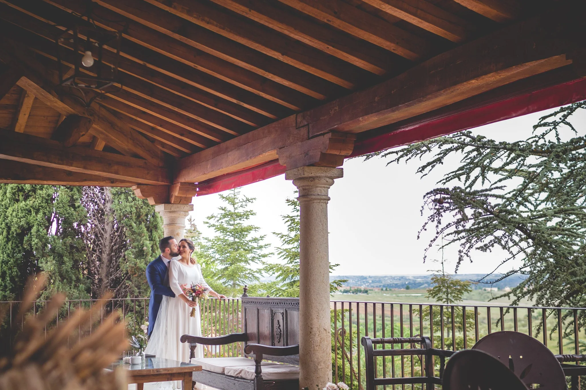 Novios posando bajo el porche con vistas al jardín en una boda en Peñarrubia de Araceli, fotografía de Pedro Zamorano.