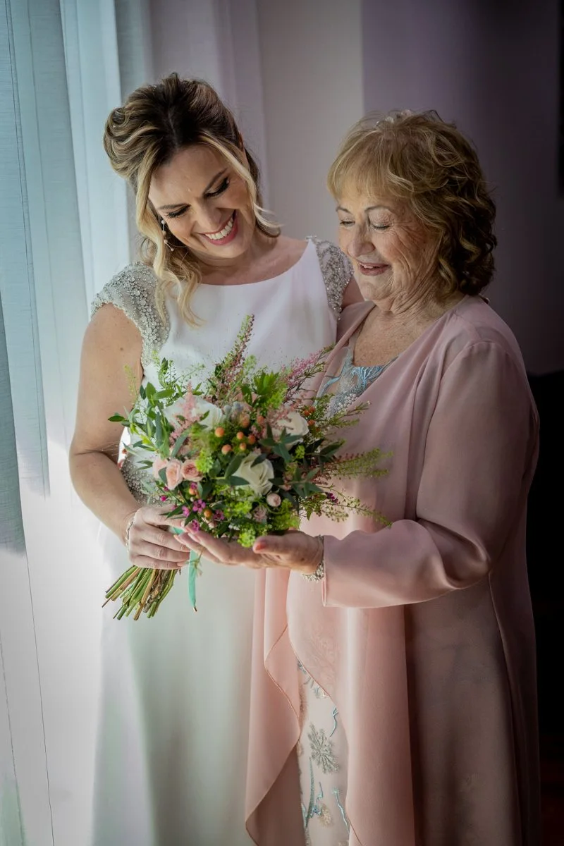 Novia mostrando el ramo a su madre en una boda en Peñarrubia de Araceli, fotografía de Pedro Zamorano.
