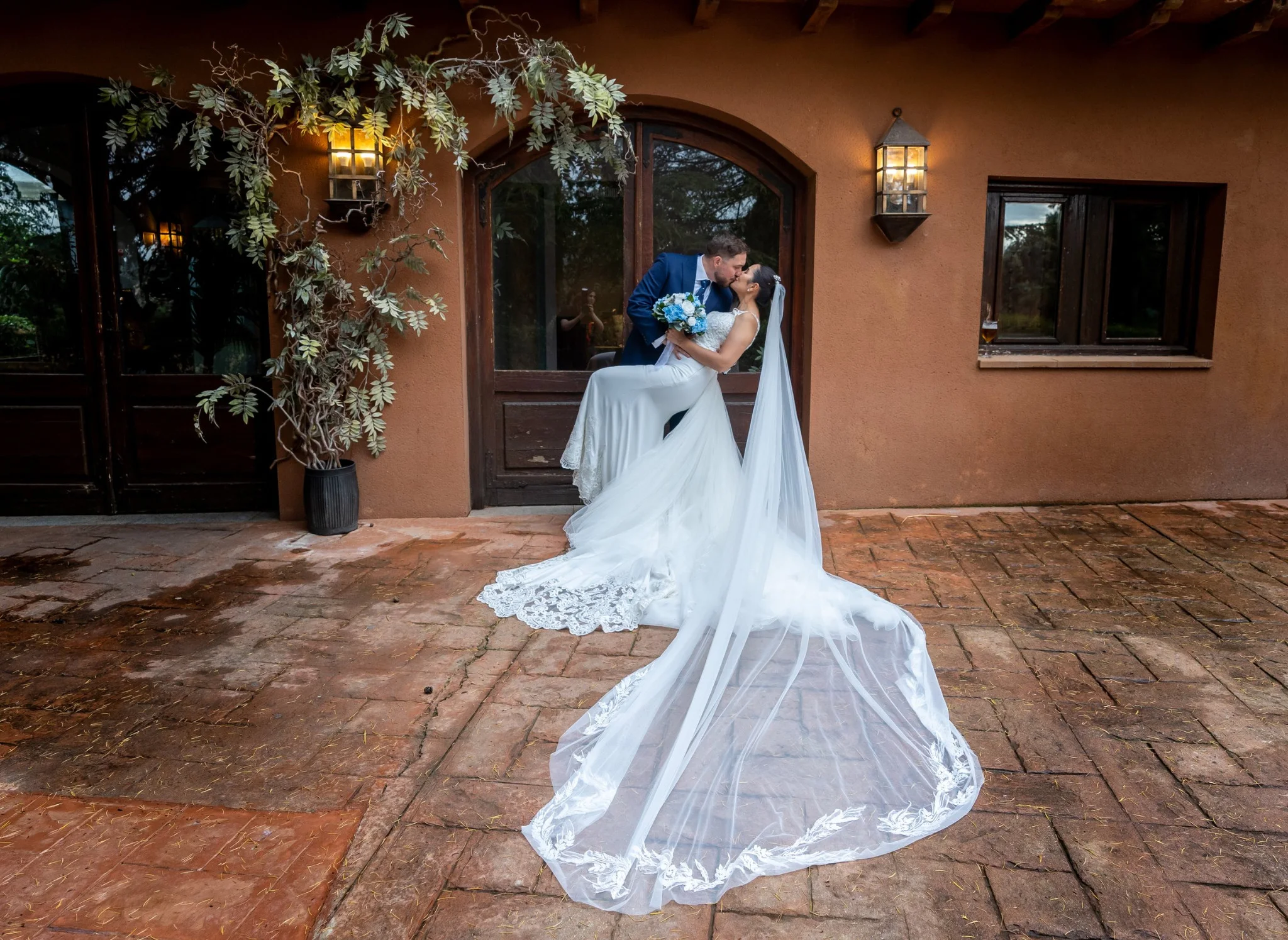 Novios abrazados ante la puerta decorada de la finca en una boda en Peñarrubia de Araceli, fotografía de Pedro Zamorano.