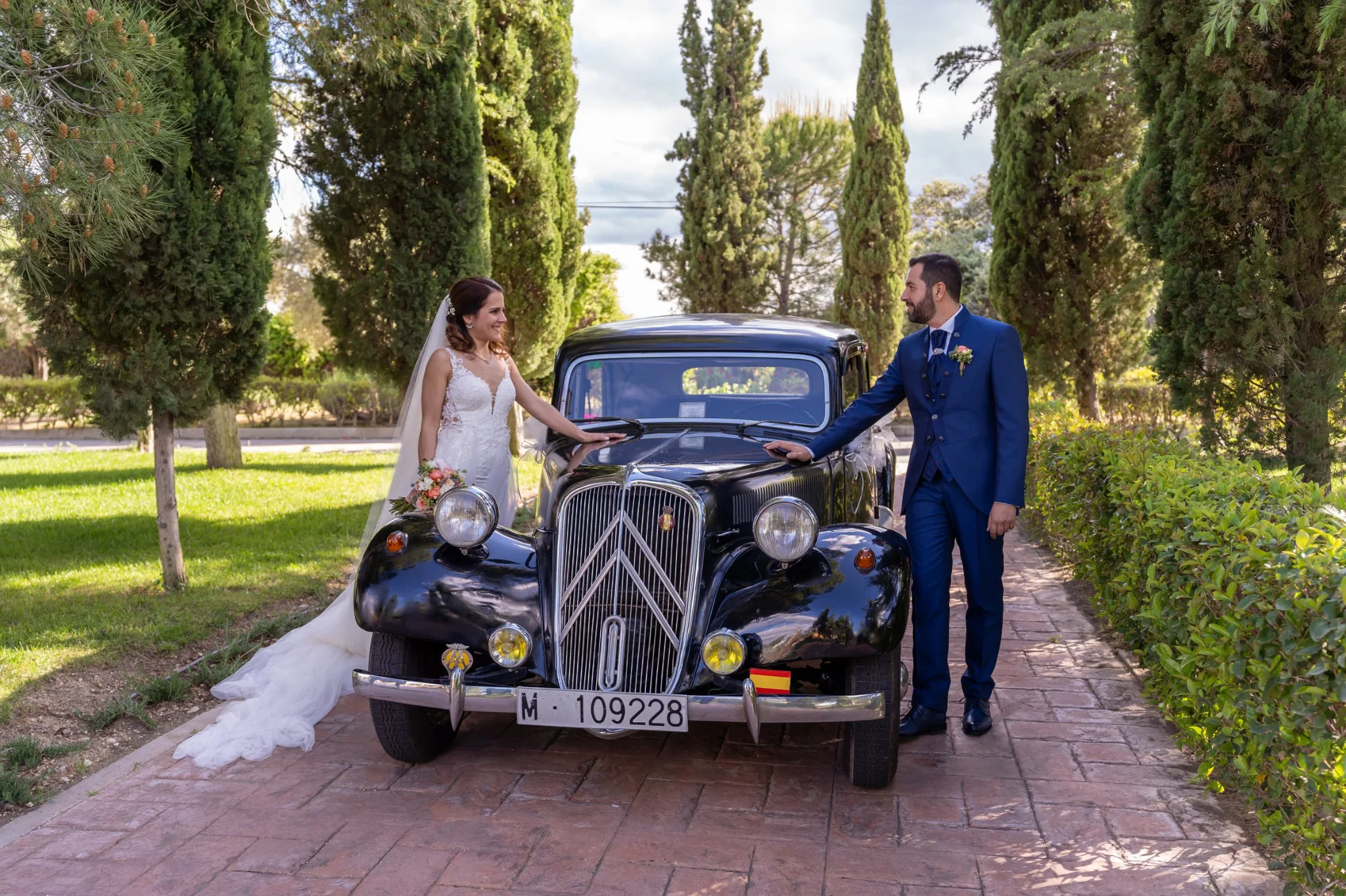 Novios posando junto a un coche clásico negro en una boda en Peñarrubia de Araceli, fotografía de Pedro Zamorano.