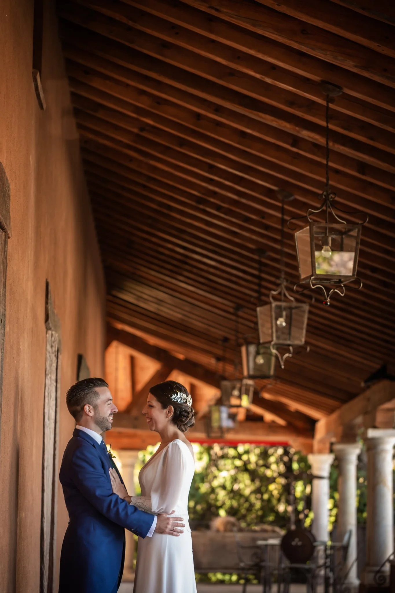 Beso de los novios bajo el porche en formato vertical en una boda en Peñarrubia de Araceli, fotografía de Pedro Zamorano.