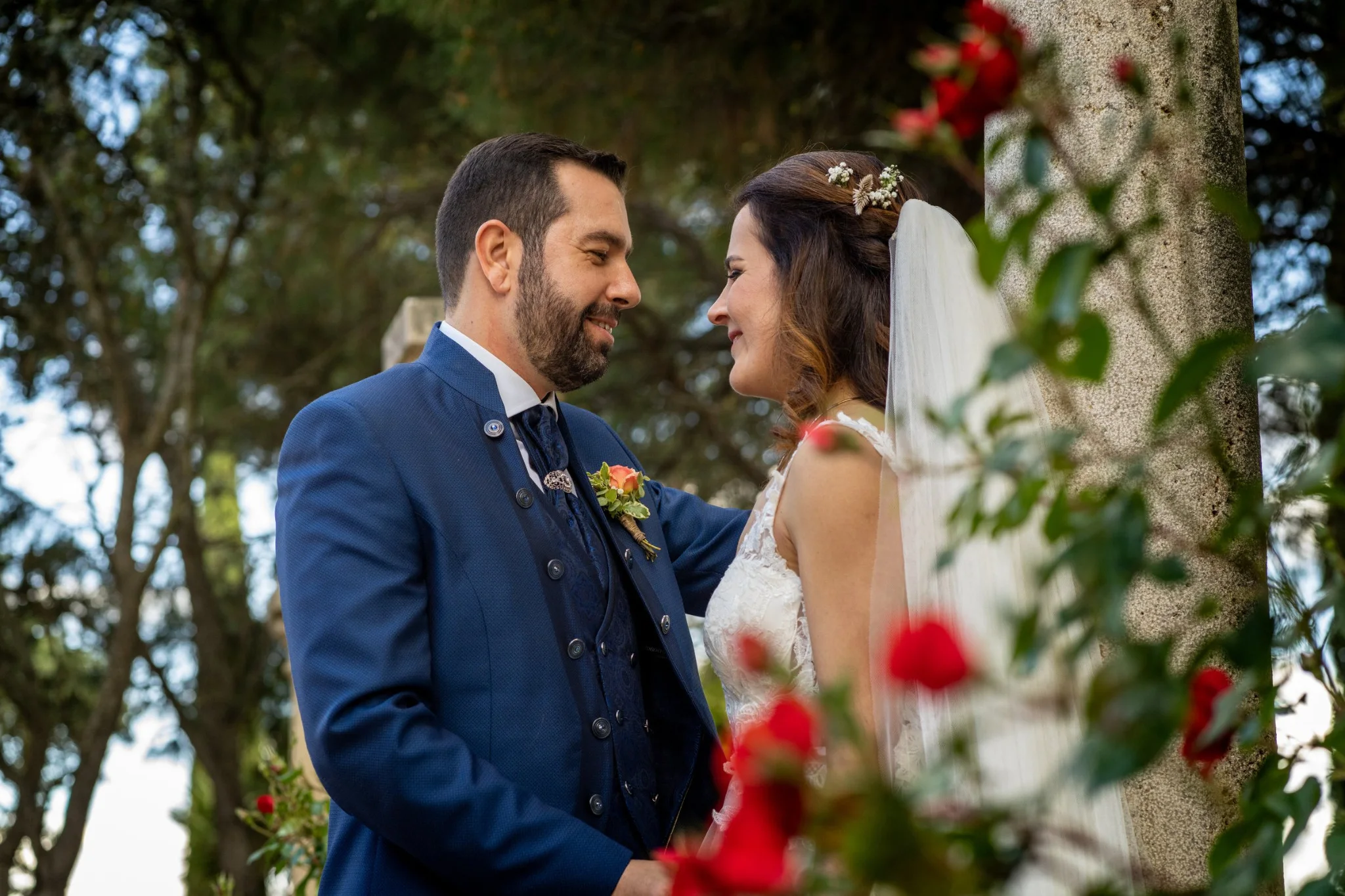 Novios mirándose entre rosales rojos en una boda en Peñarrubia de Araceli, fotografía de Pedro Zamorano.