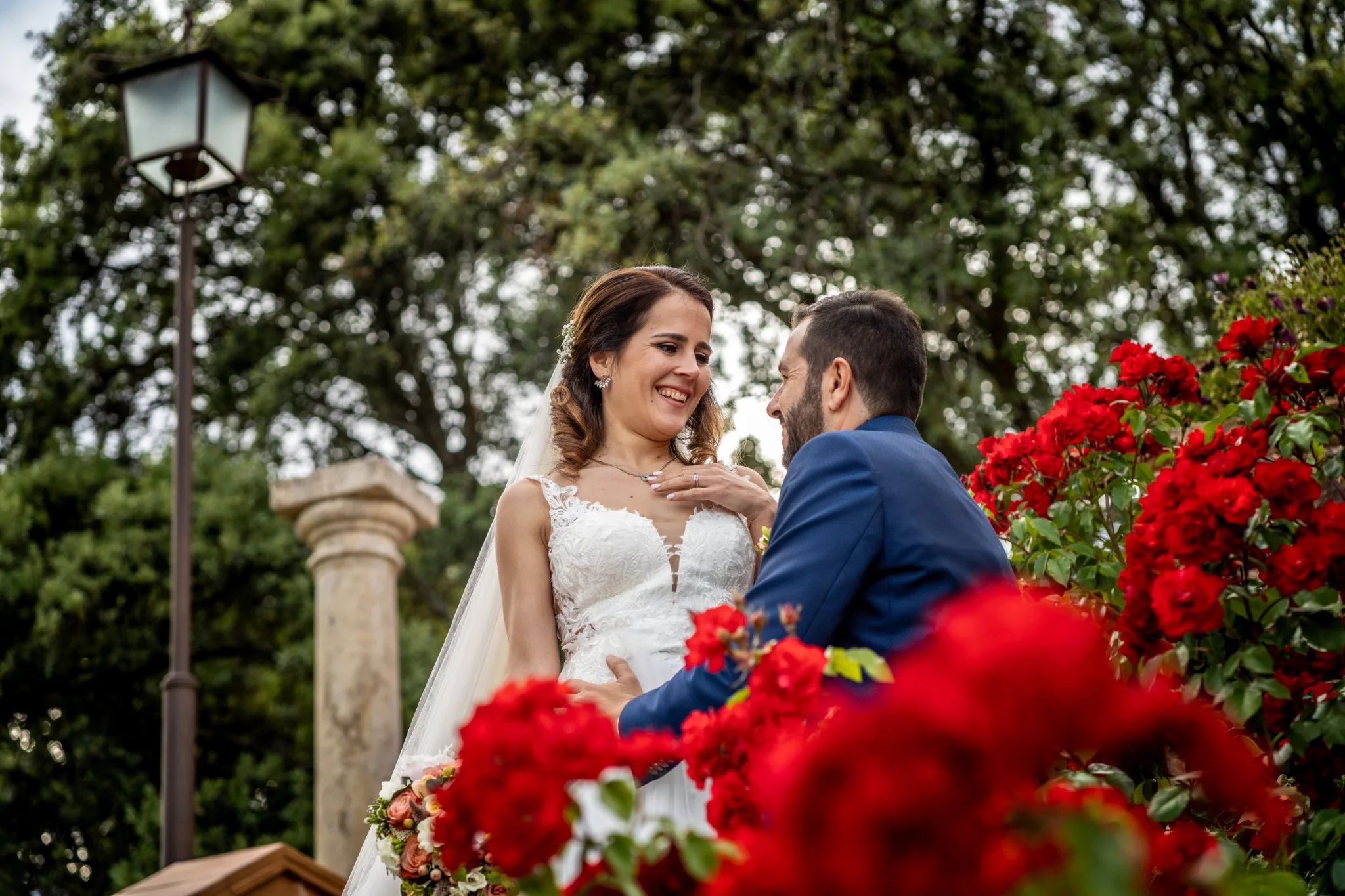 Retrato de los novios entre flores rojas en una boda en Peñarrubia de Araceli, fotografía de Pedro Zamorano.