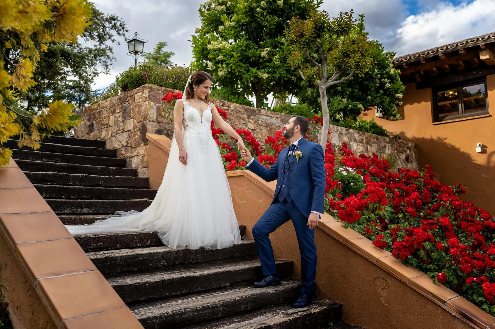 Novios posando en la escalinata de la finca en una boda en Peñarrubia de Araceli, fotografía de Pedro Zamorano.