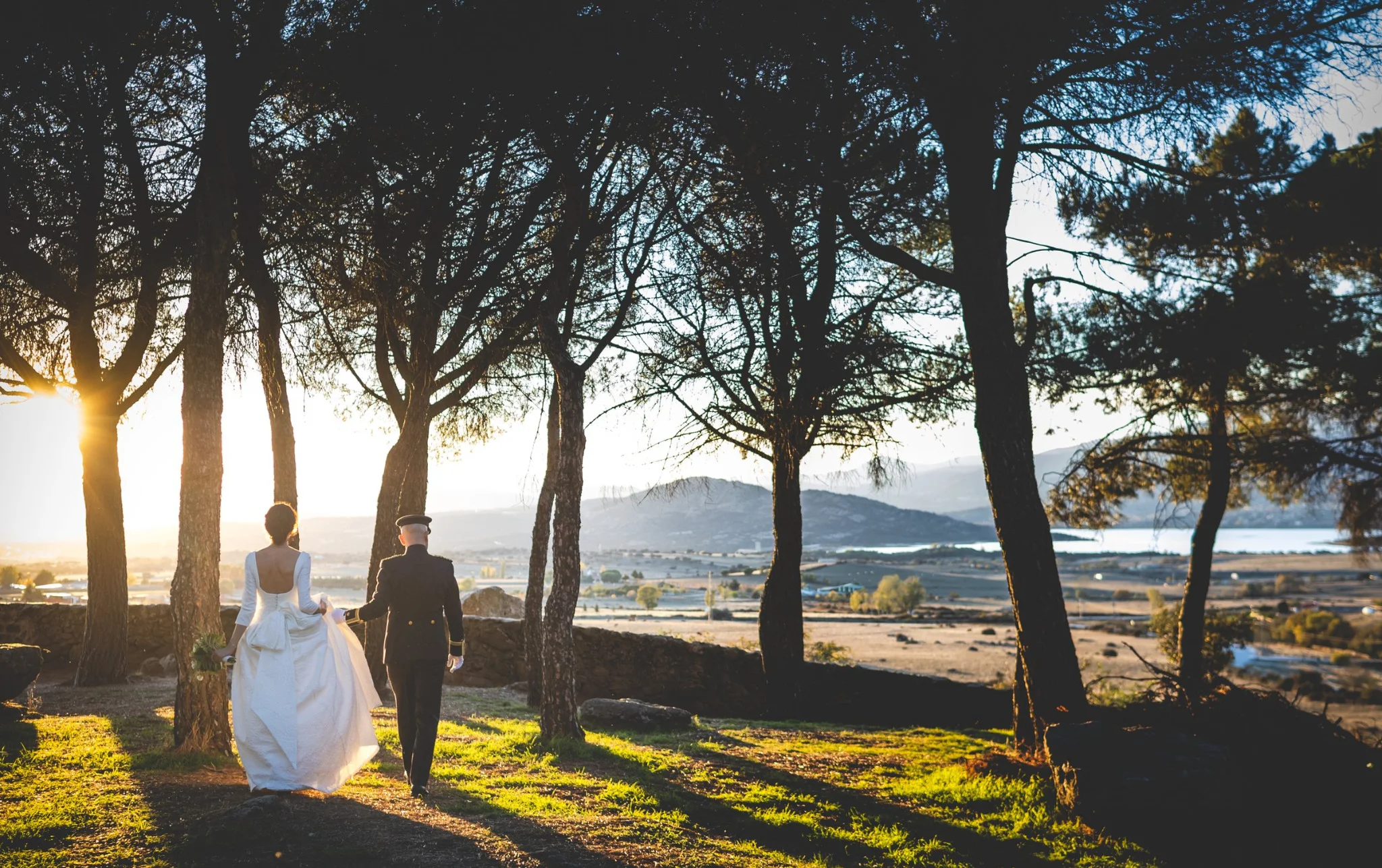 Novios caminando entre árboles al atardecer en una boda en Peñarrubia de Araceli, fotografía de Pedro Zamorano.