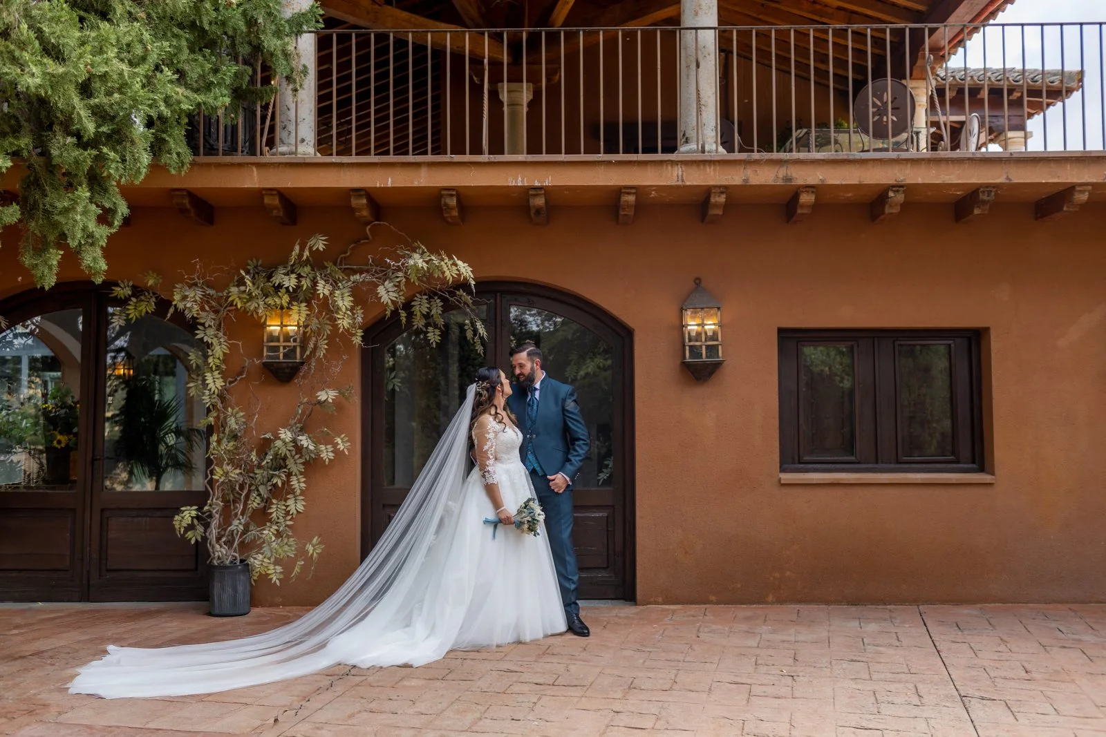Novios posando frente a la entrada floral de la finca en una boda en Peñarrubia de Araceli, fotografía de Pedro Zamorano.
