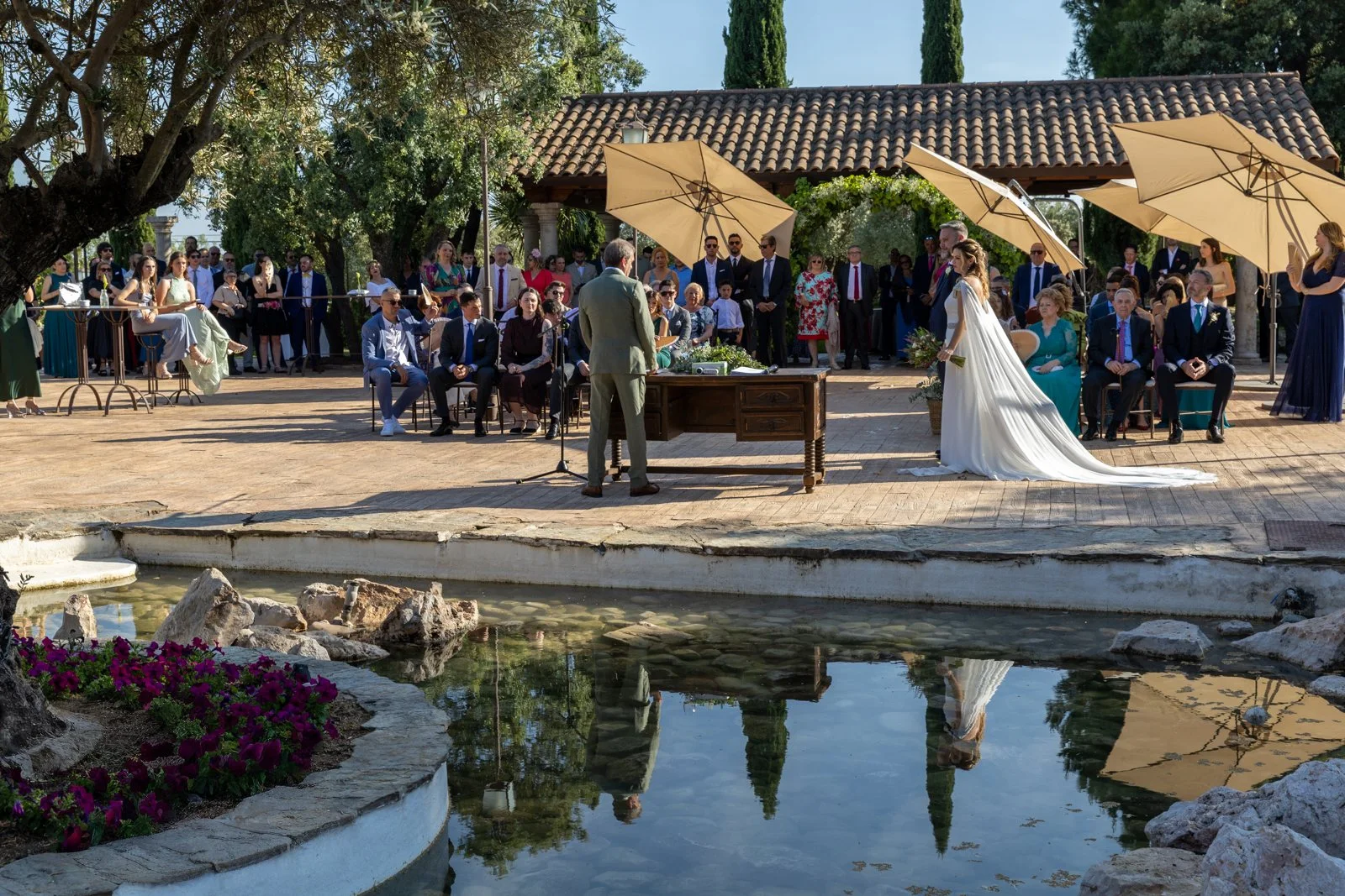 Vista general de la ceremonia civil junto al estanque en una boda en Peñarrubia de Araceli, fotografía de Pedro Zamorano.