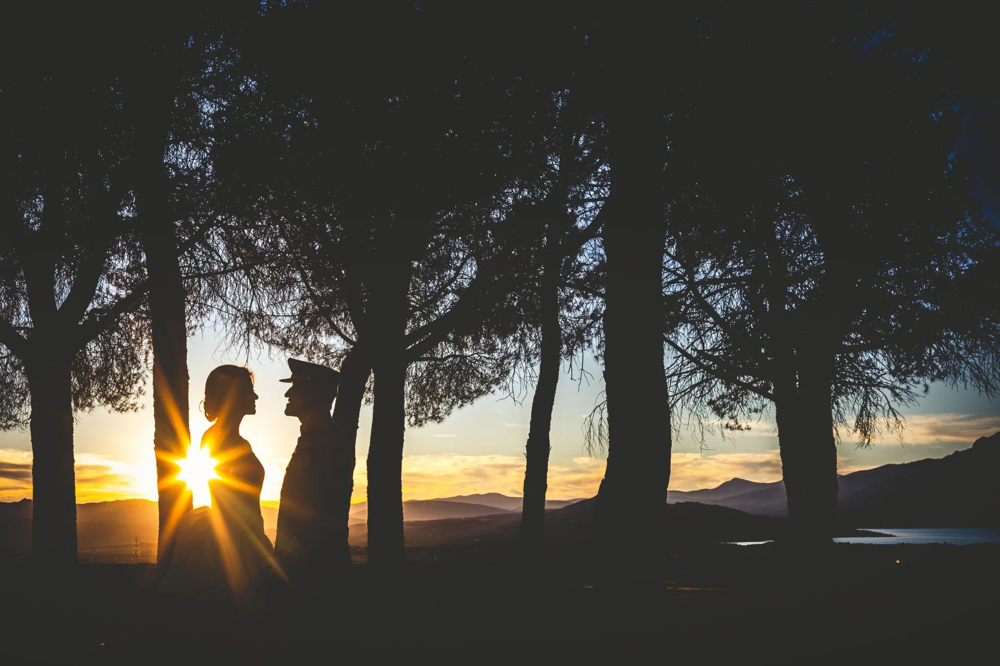 Silueta de los novios con el sol entre los árboles en una boda en Peñarrubia de Araceli, fotografía de Pedro Zamorano.