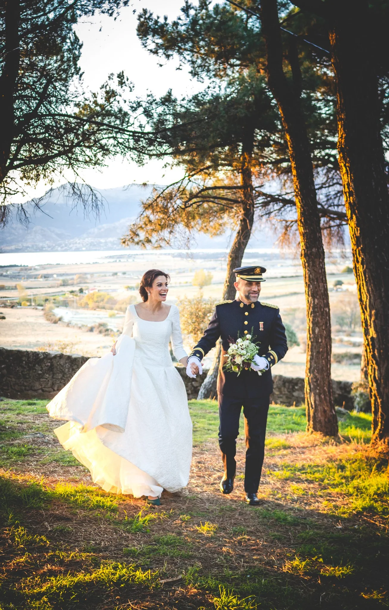 Novios caminando al atardecer en formato vertical en una boda en Peñarrubia de Araceli, fotografía de Pedro Zamorano.