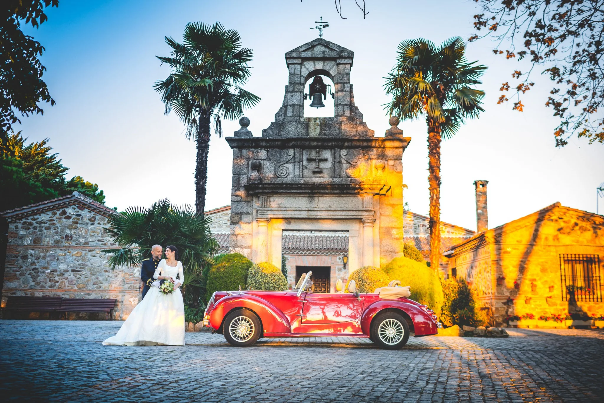 Novios y coche clásico frente a la capilla al atardecer en una boda en Peñarrubia de Araceli, fotografía de Pedro Zamorano.