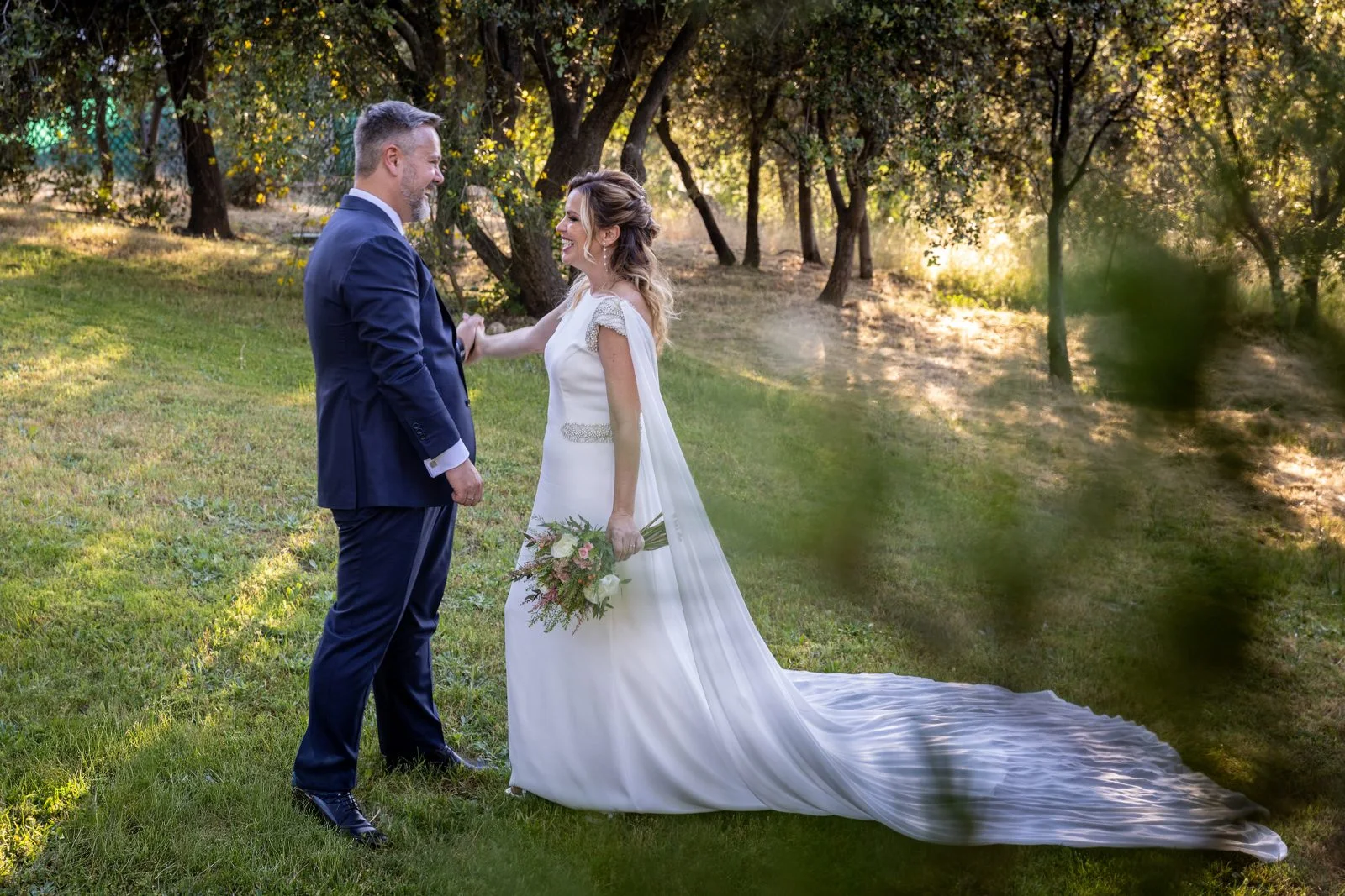 Novios de pie en el jardín con luz cálida en una boda en Peñarrubia de Araceli, fotografía de Pedro Zamorano.