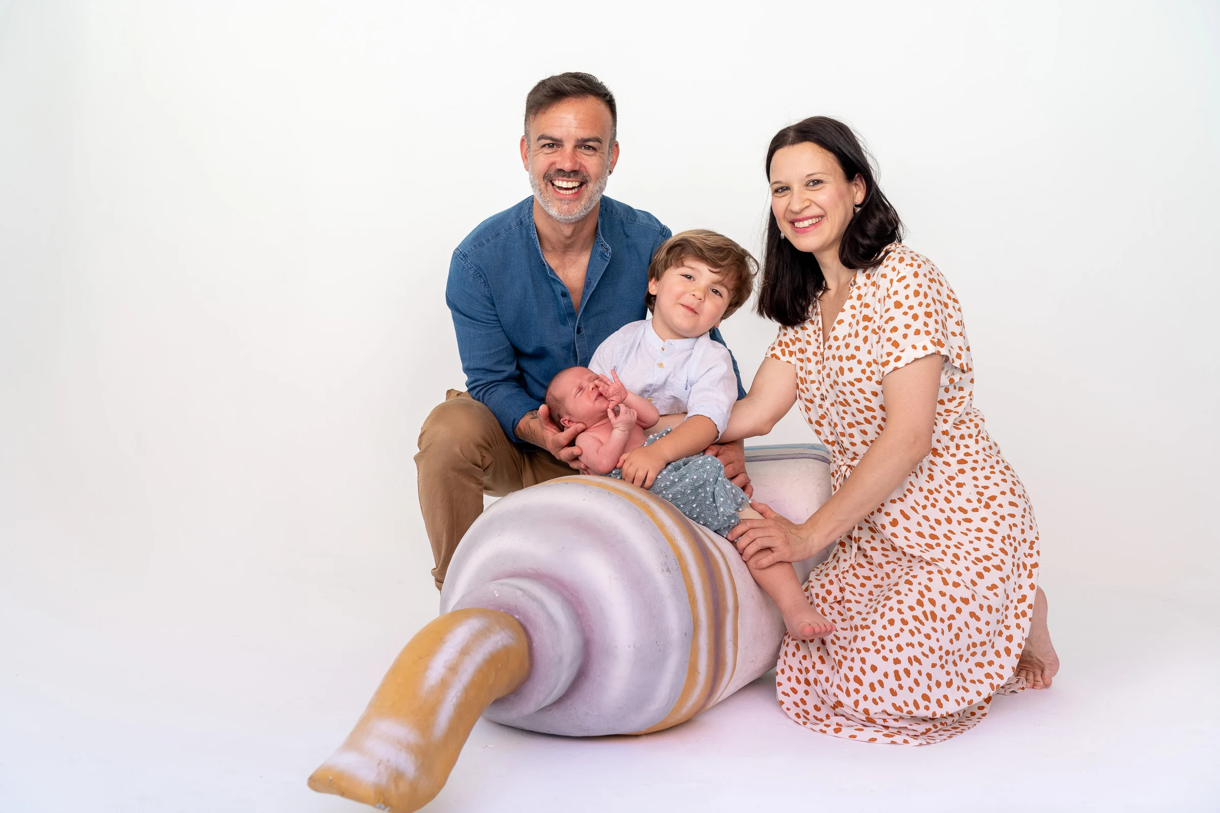 Padres y hermano mayor posan con su bebé en un retrato familiar de estudio.