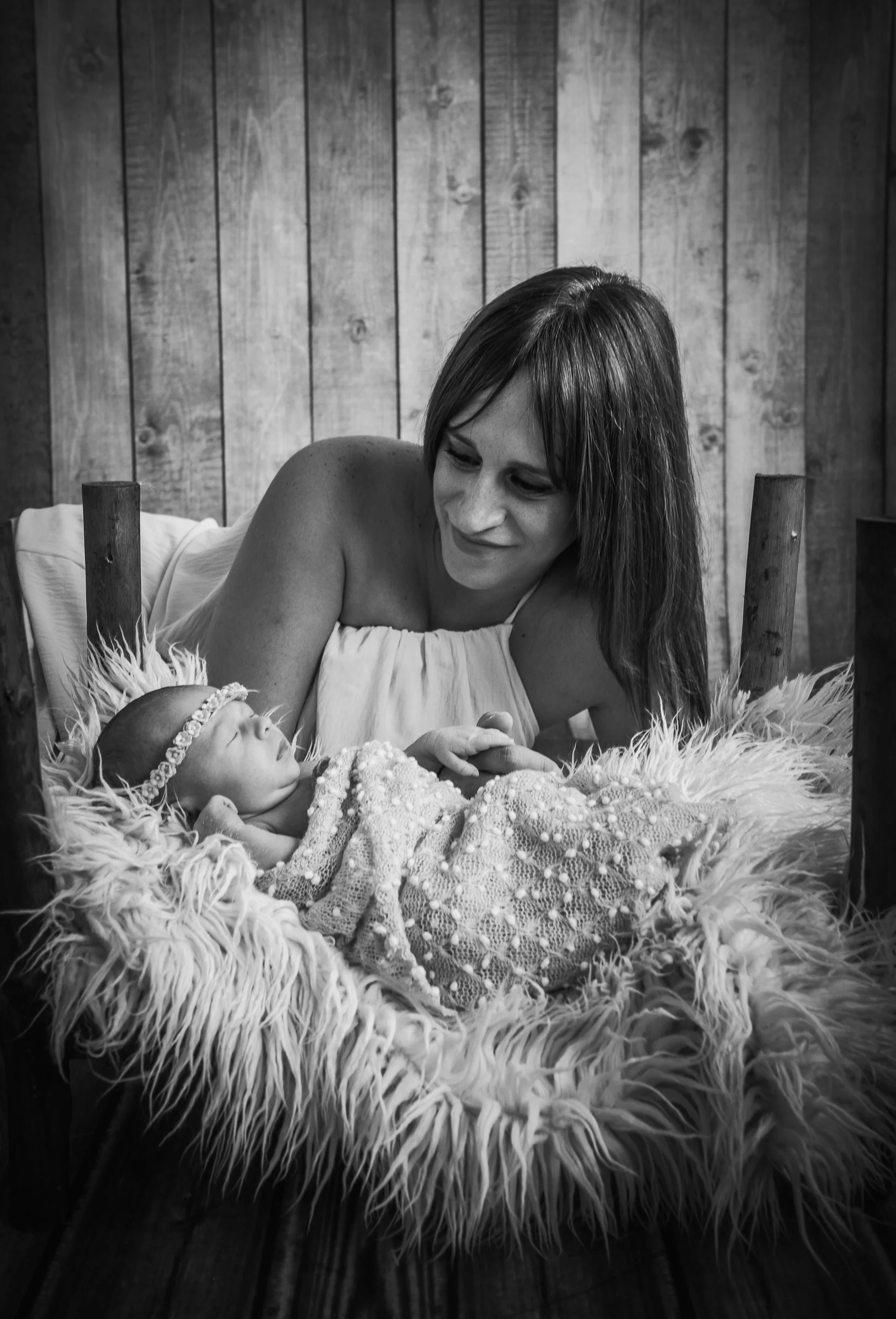 Retrato en blanco y negro de una madre mirando a su recién nacido sobre un nido de pelo.