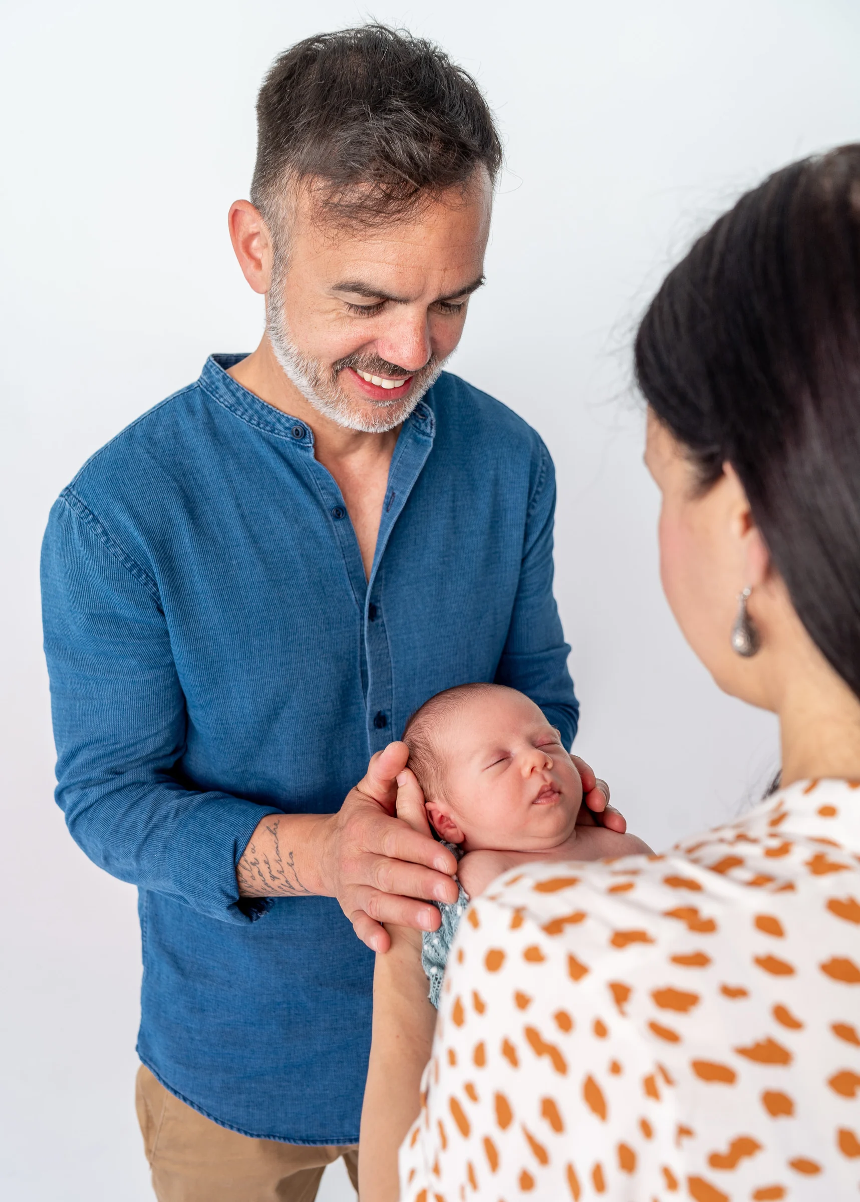 Primer plano del padre con su recién nacido en brazos durante la sesión familiar.