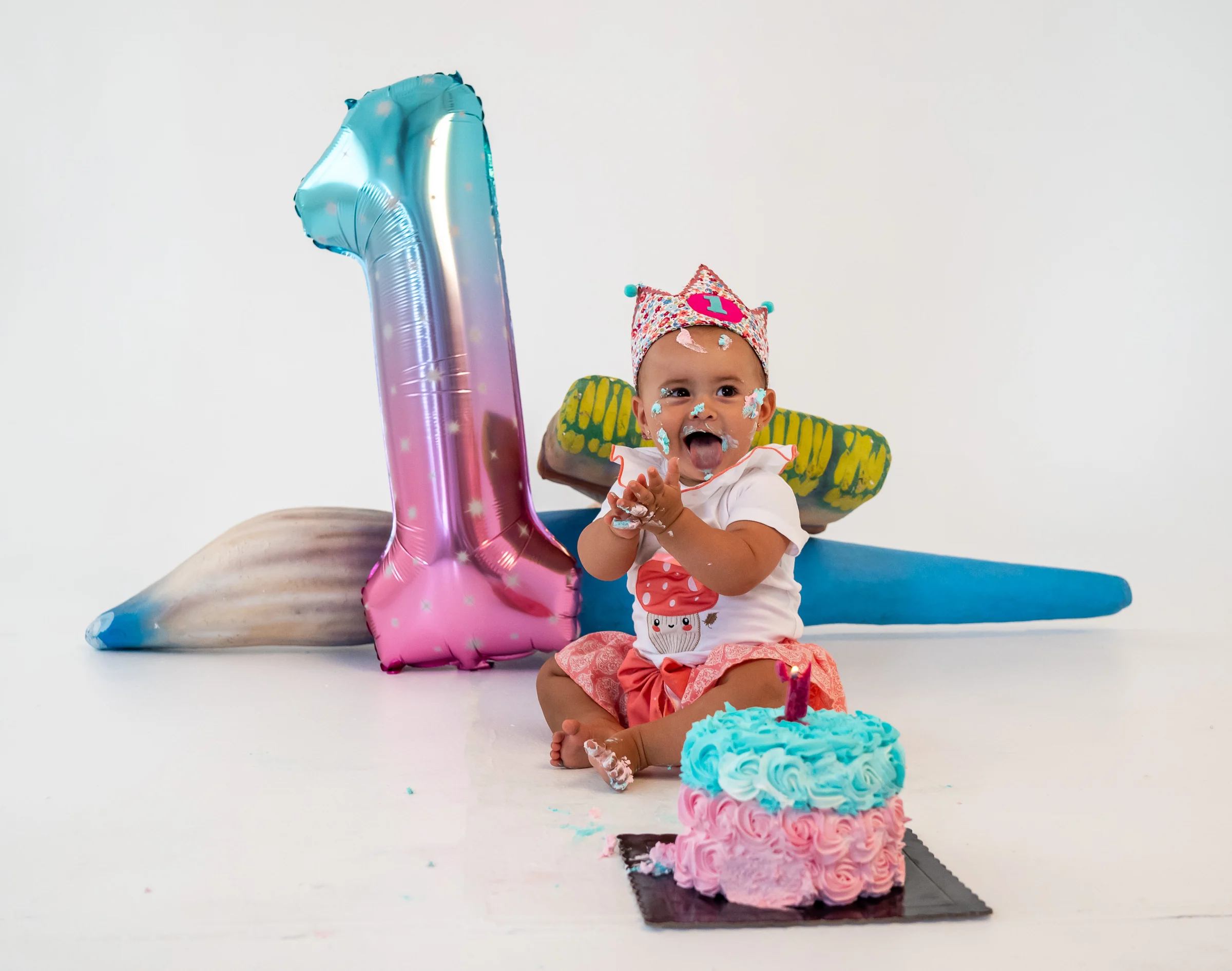 Bebé de un año con tarta y decoración de cumpleaños en estudio blanco.
