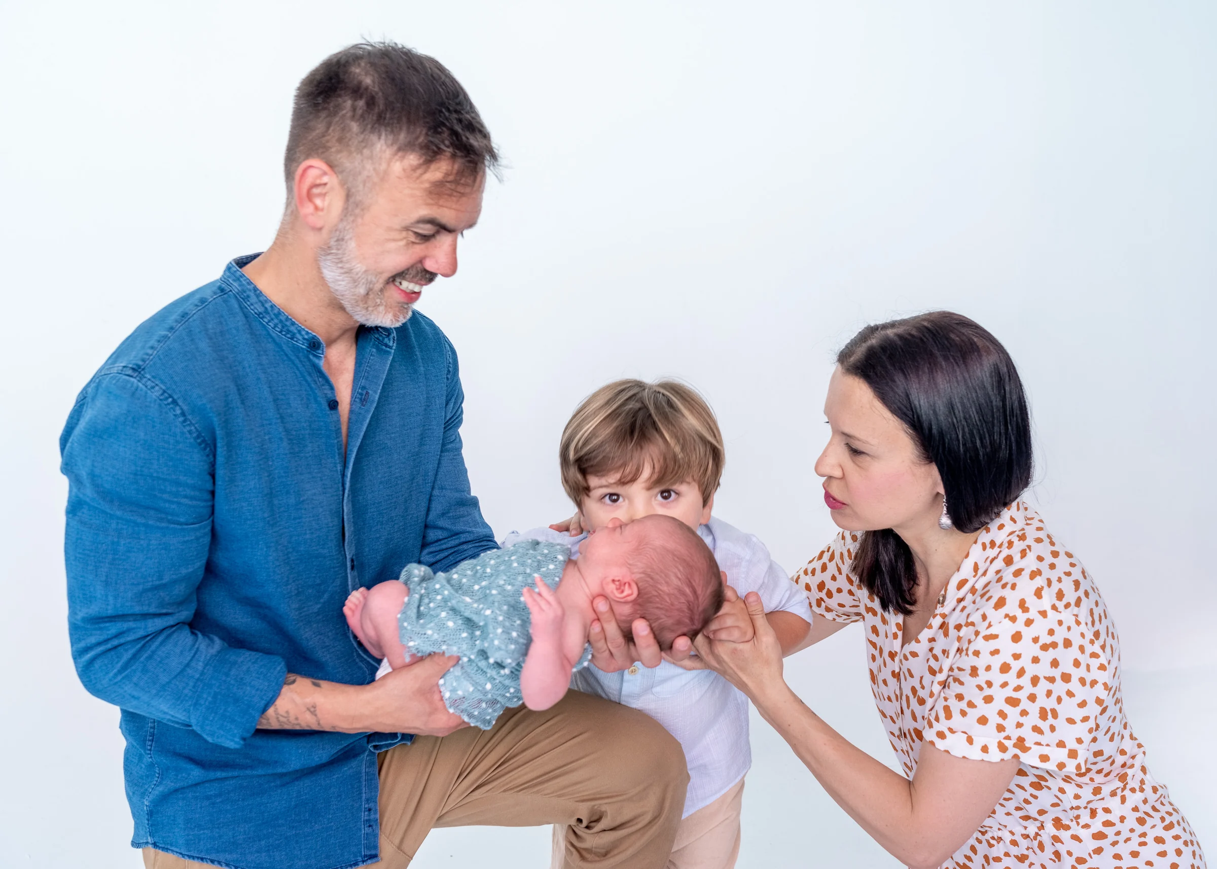 Familia con padre, madre, hijo mayor y recién nacido en una fotografía de estudio.