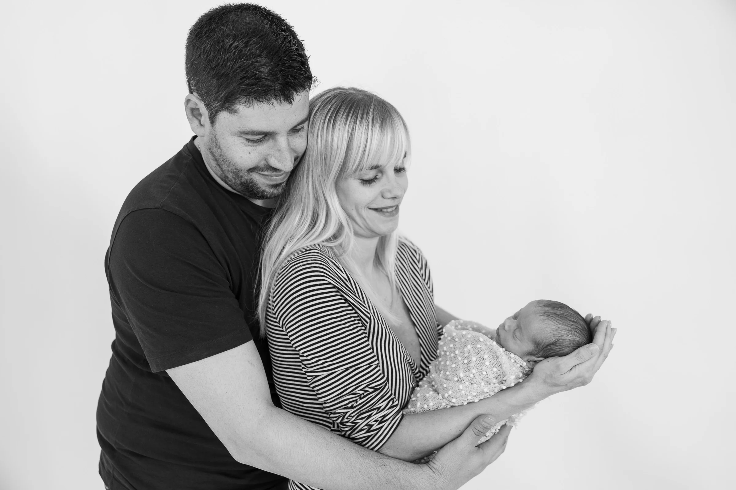 Retrato en blanco y negro de una pareja sosteniendo a su recién nacido.